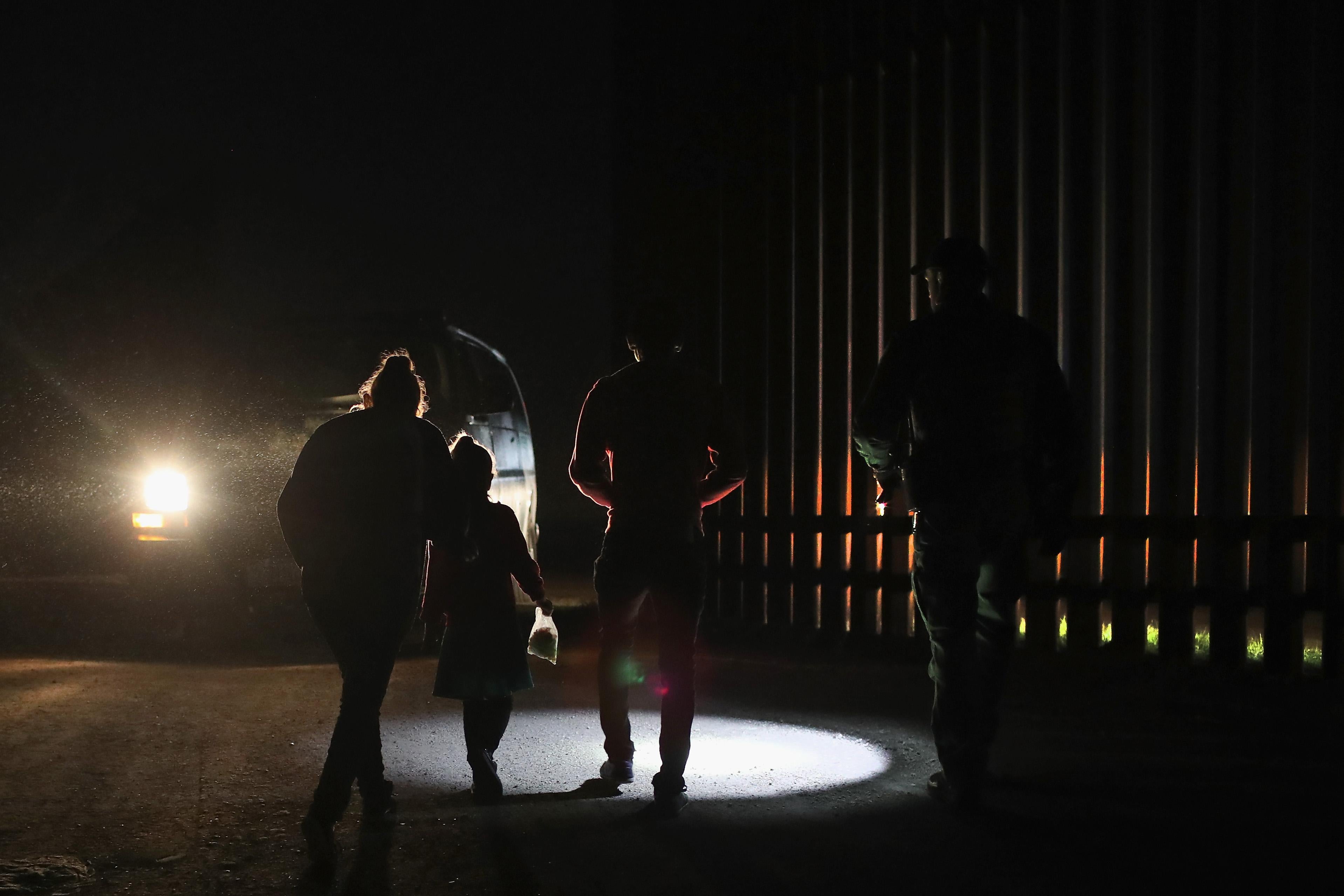 A Honduran mother walks with her children next to the U.S.-Mexico border fence as they turned themselves in to Border Patrol agents on February 22, 2018 near Penitas, Texas. 