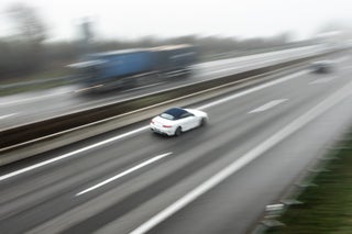 A white car races down a highway.