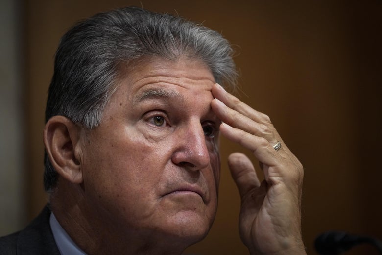 Manchin holds his hand to his forehead. 
