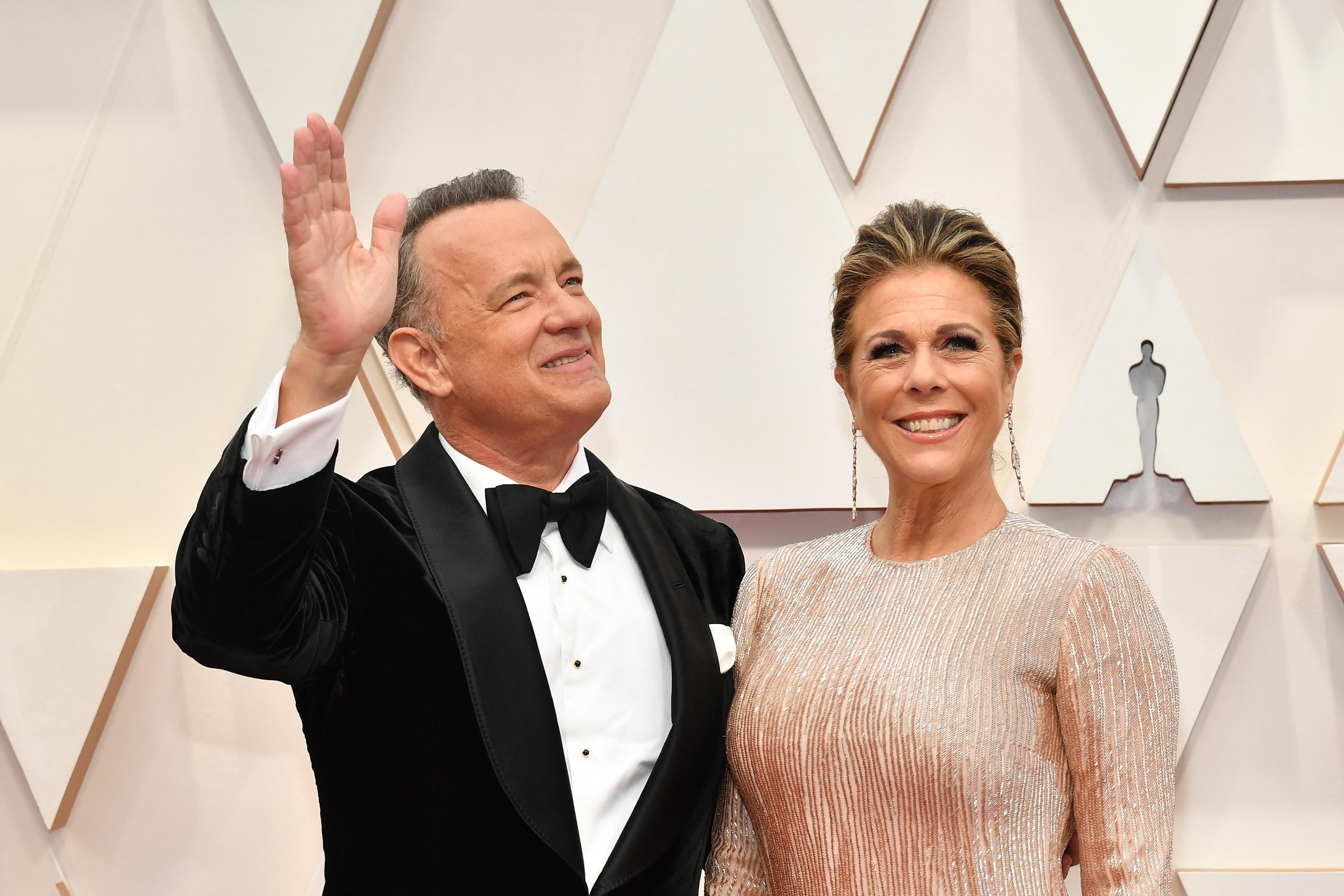 Tom Hanks, in a tuxedo, and Rita Wilson, in a beige evening gown, on the red carpet at the academy awards.