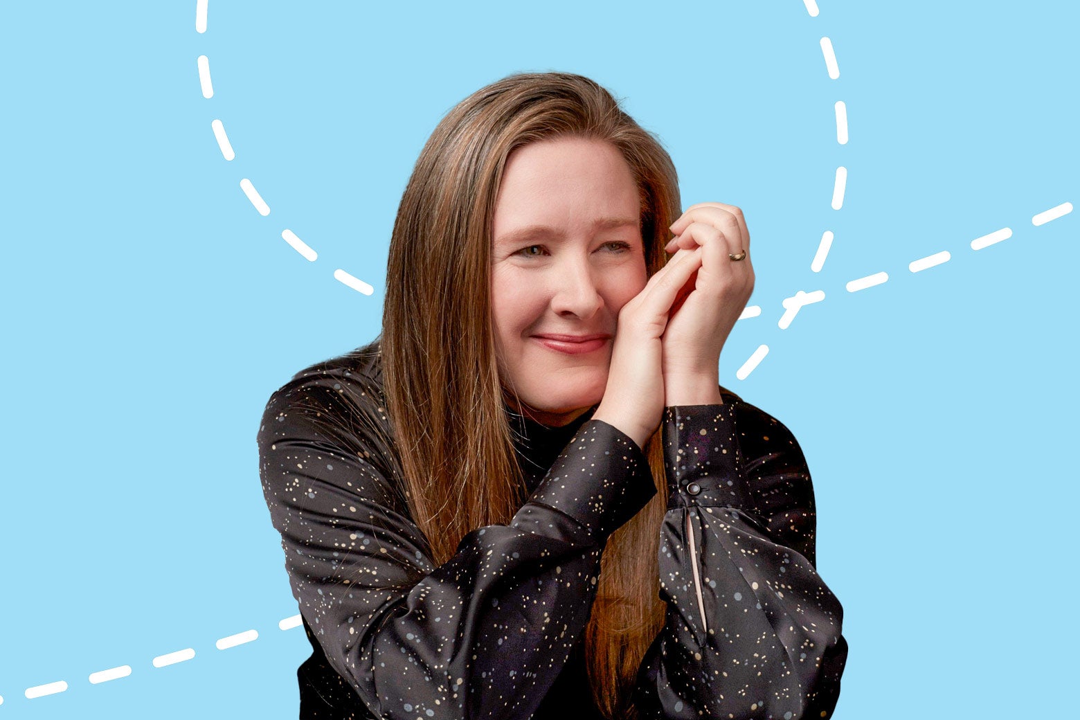 Sarah Ruhl smiling and looking off-camera. She with her hands folded near her face and is leaning her head on her hands. She's wearing a sparkly black long-sleeve top. 
