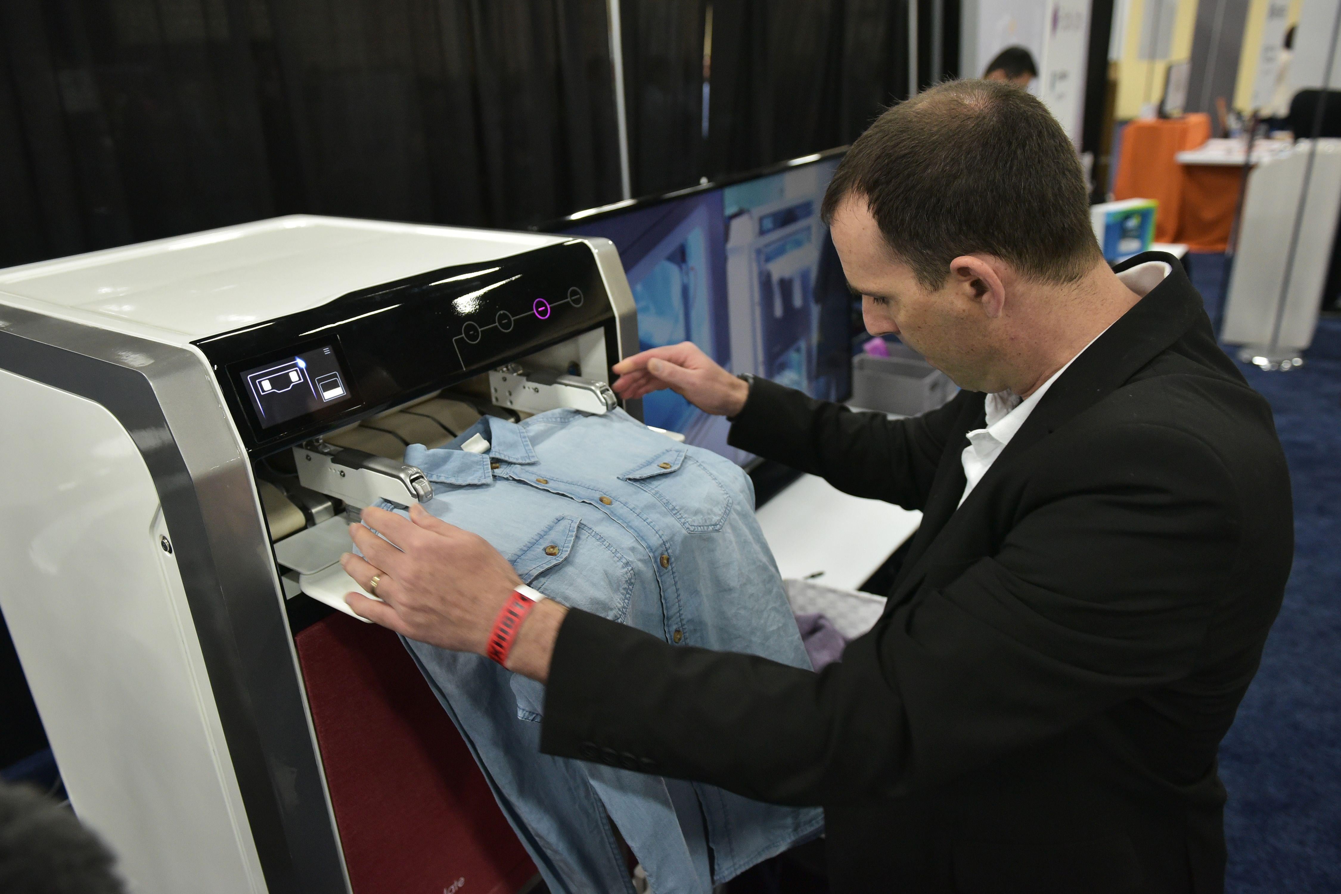 An exhibitor demostrates the FoldiMate laundry folding machine during the CES Unveiled preview event at the Mandalay Bay Convention Center during CES 2018 in Las Vegas on January 7, 2018. / AFP PHOTO / MANDEL NGAN        (Photo credit should read MANDEL NGAN/AFP/Getty Images)