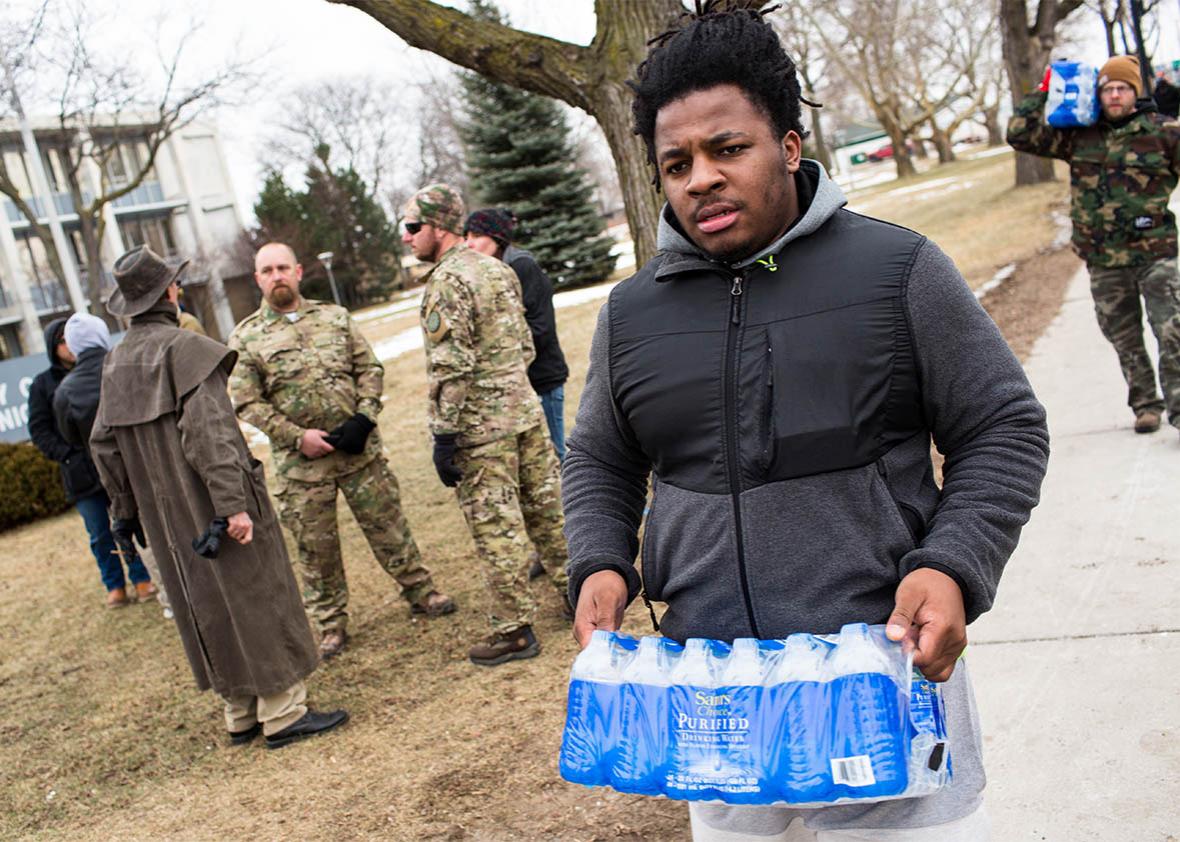 Darius Simpson, an Eastern Michigan University student from Akron, Ohio, carries water he brought to donate for Flint residents during a rally, Jan. 24, 2016, at Flint City Hall in Flint, Michigan.