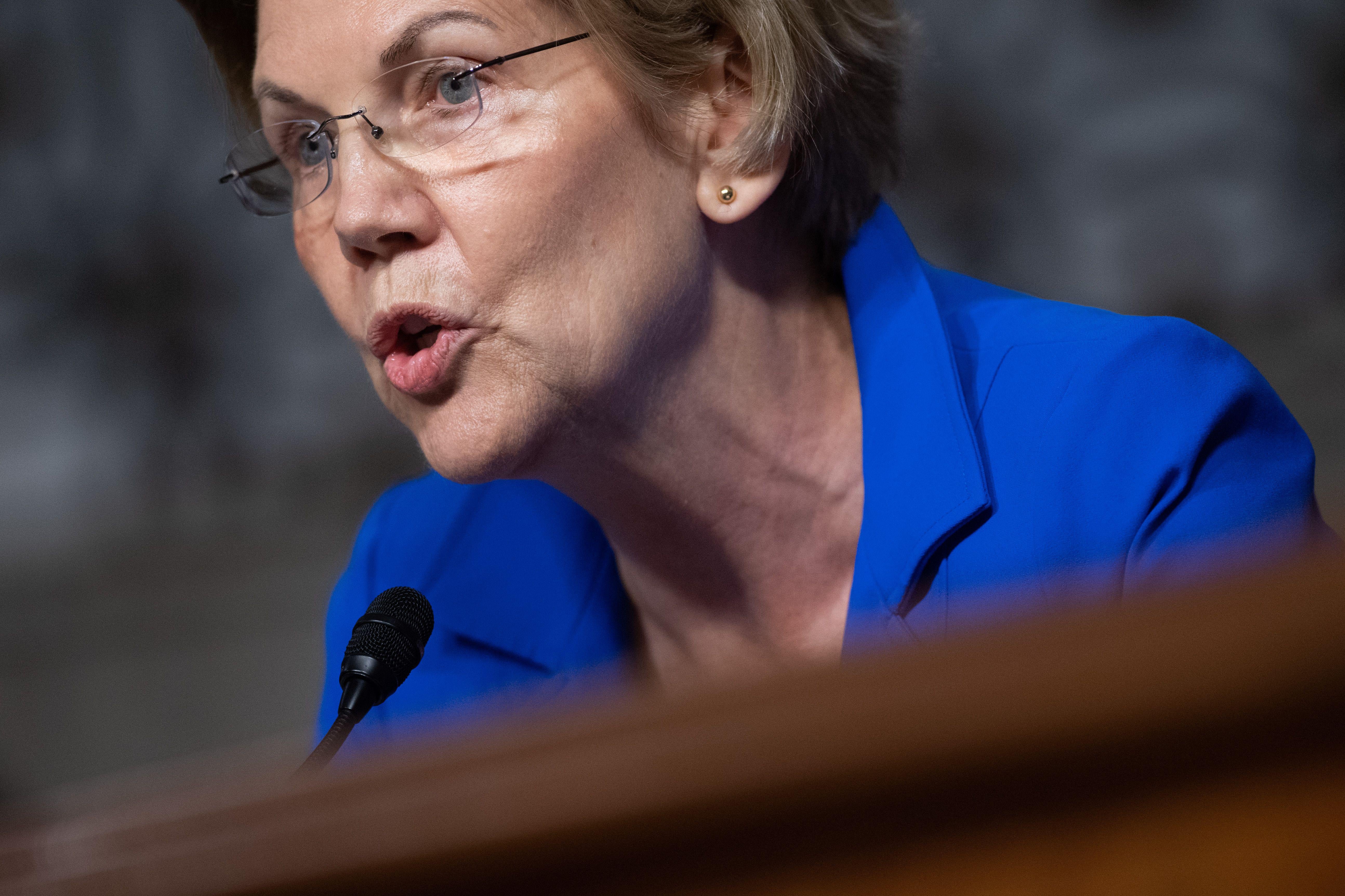 Warren speaks into a microphone at a Senate confirmation hearing