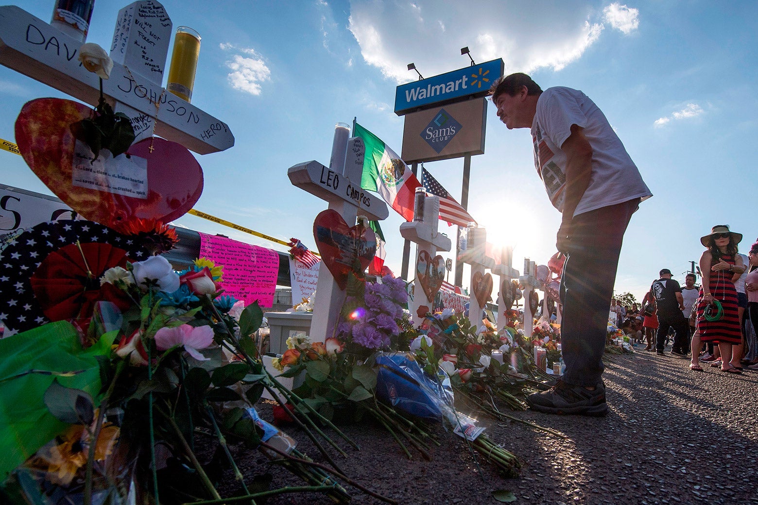 People pay their respects at a memorial of crosses and flowers honoring the shooting victims.