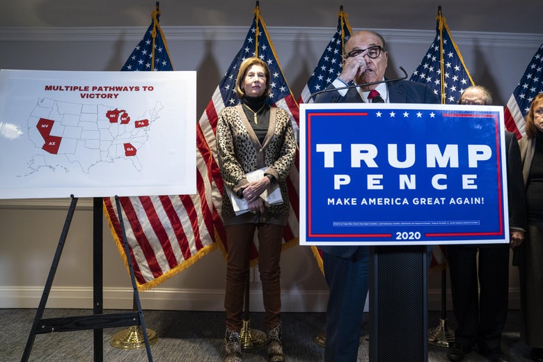 Rudy Giuliani pushes up his glasses as he speaks at a podium during a press conference. Behind him, Sidney Powell stands beside an electoral map titled "MULTIPLE PATHWAYS TO VICTORY" with several states highlighted in red.