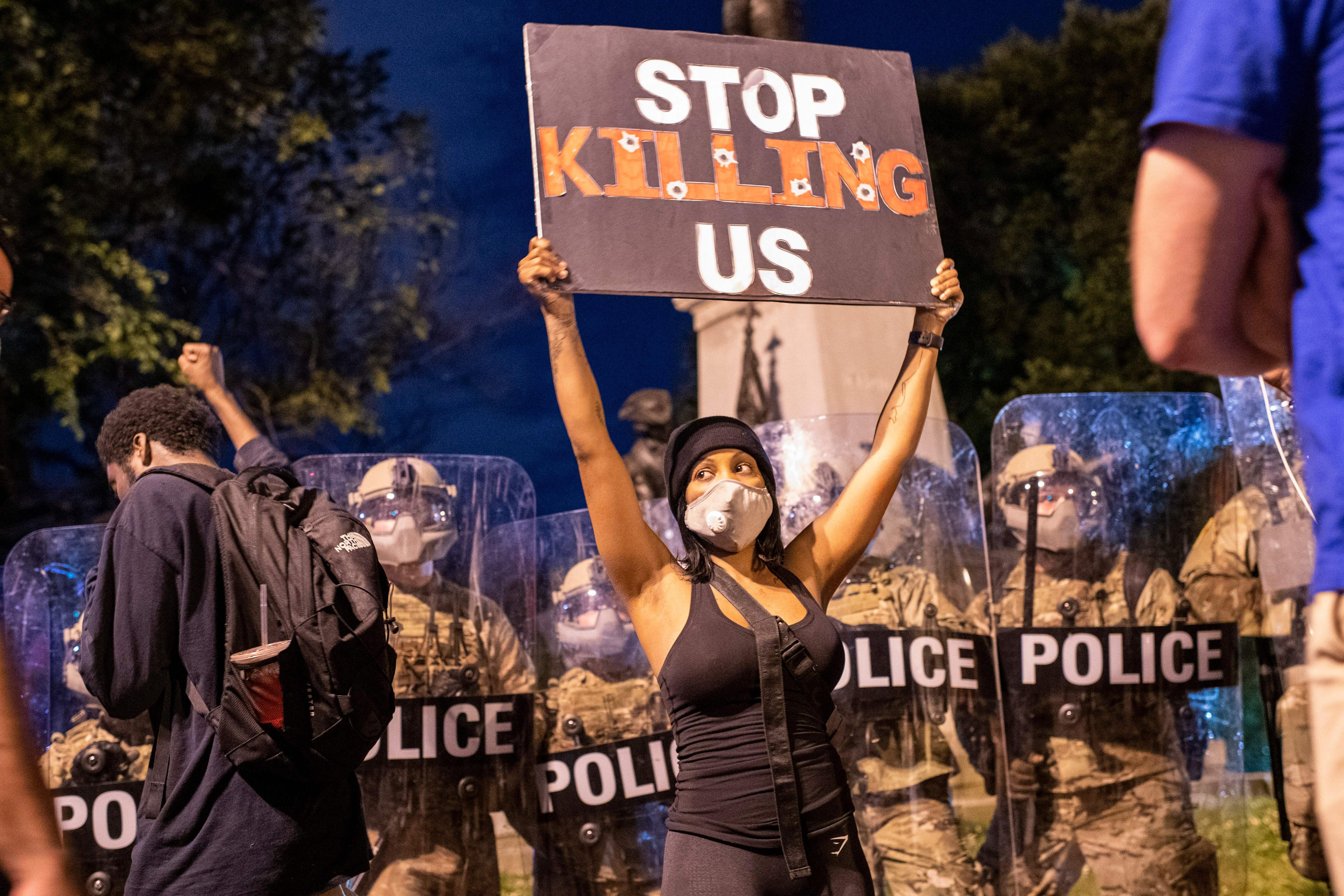 A demonstrator holds a sign reading "Stop Killing Us" in front of a police line outside of the White House on May 30, 2020 in Washington, D.C.
