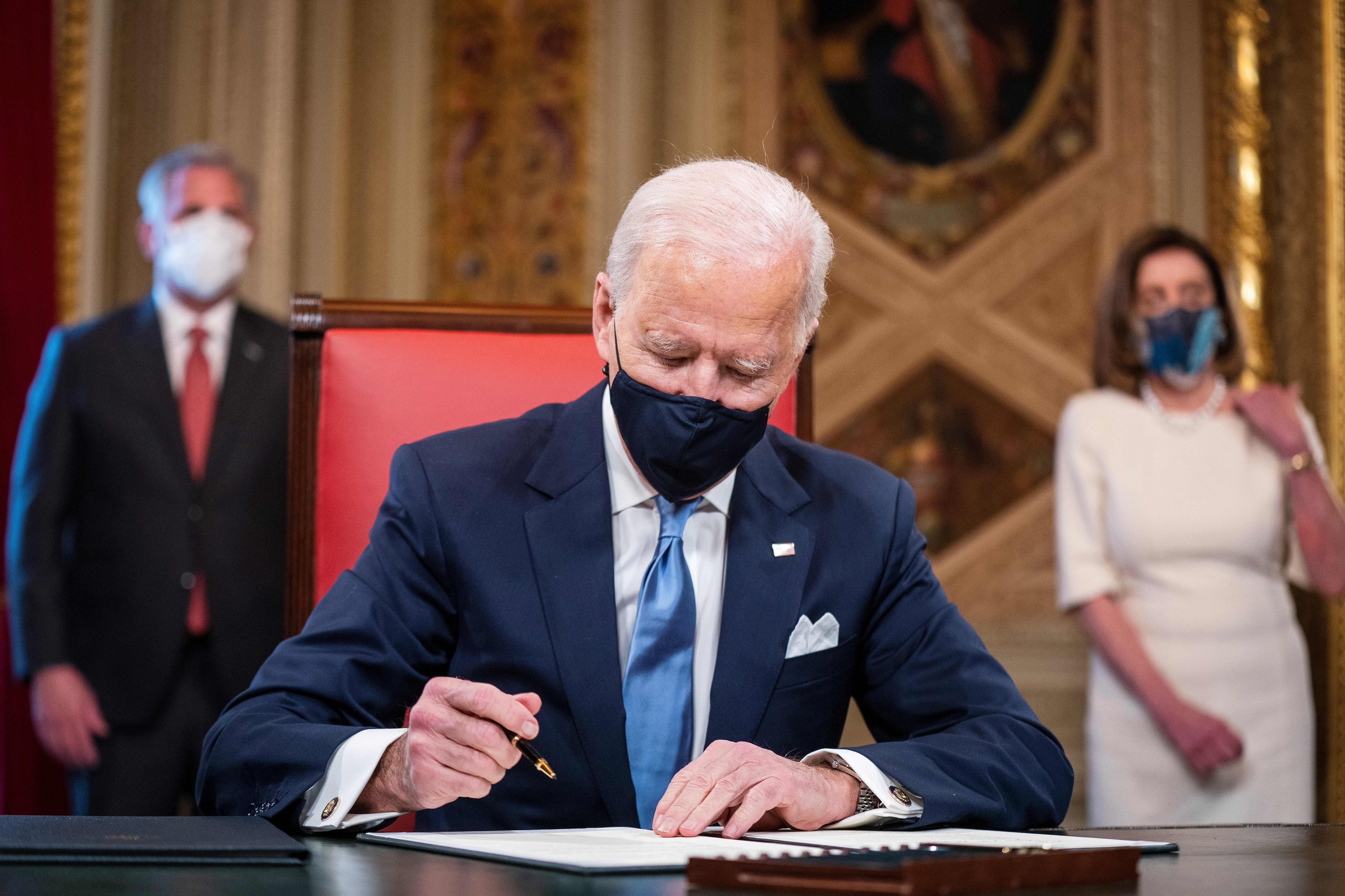 Biden in a mask signing a document 
