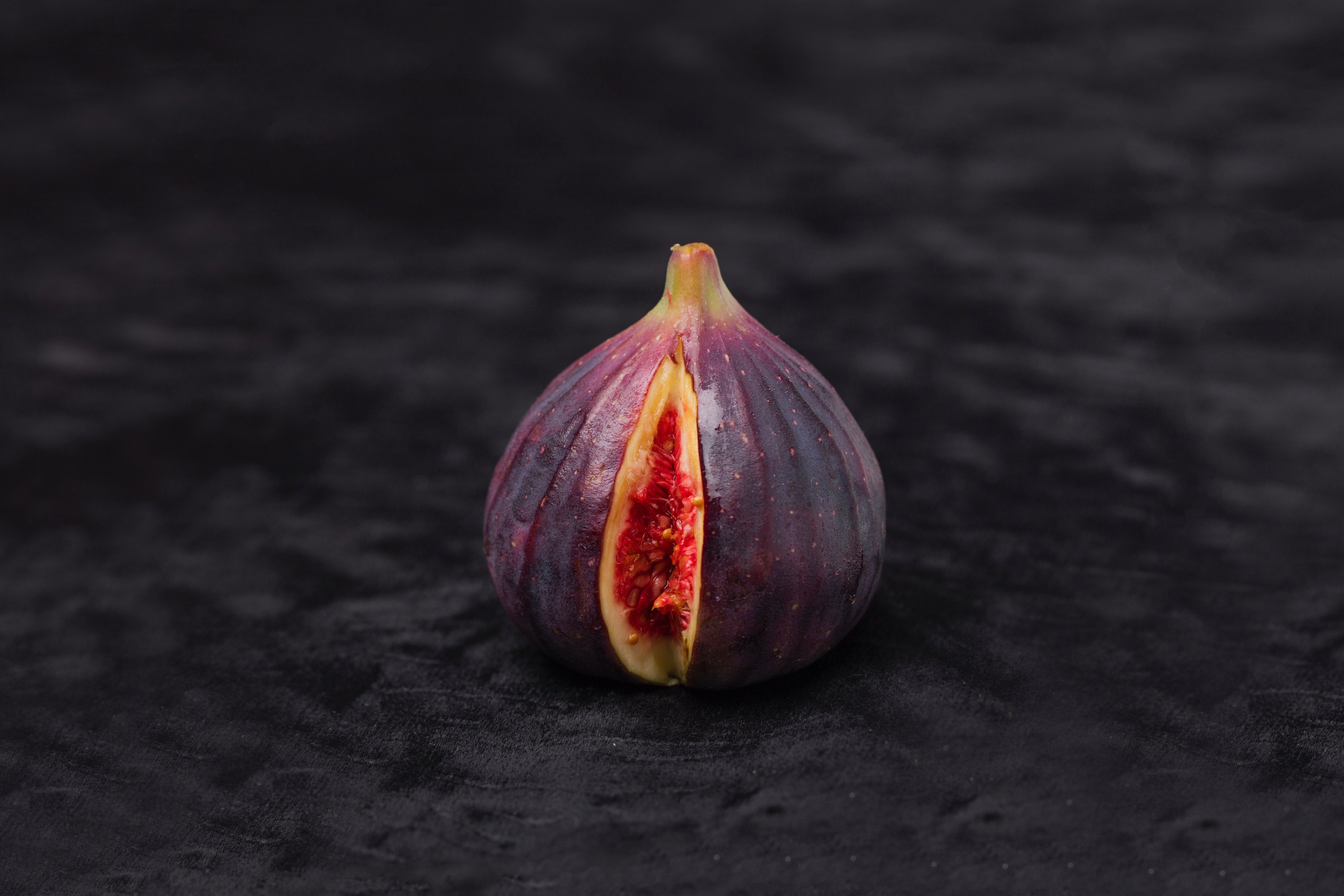 A fig with a slice cut out. The inside is red. 