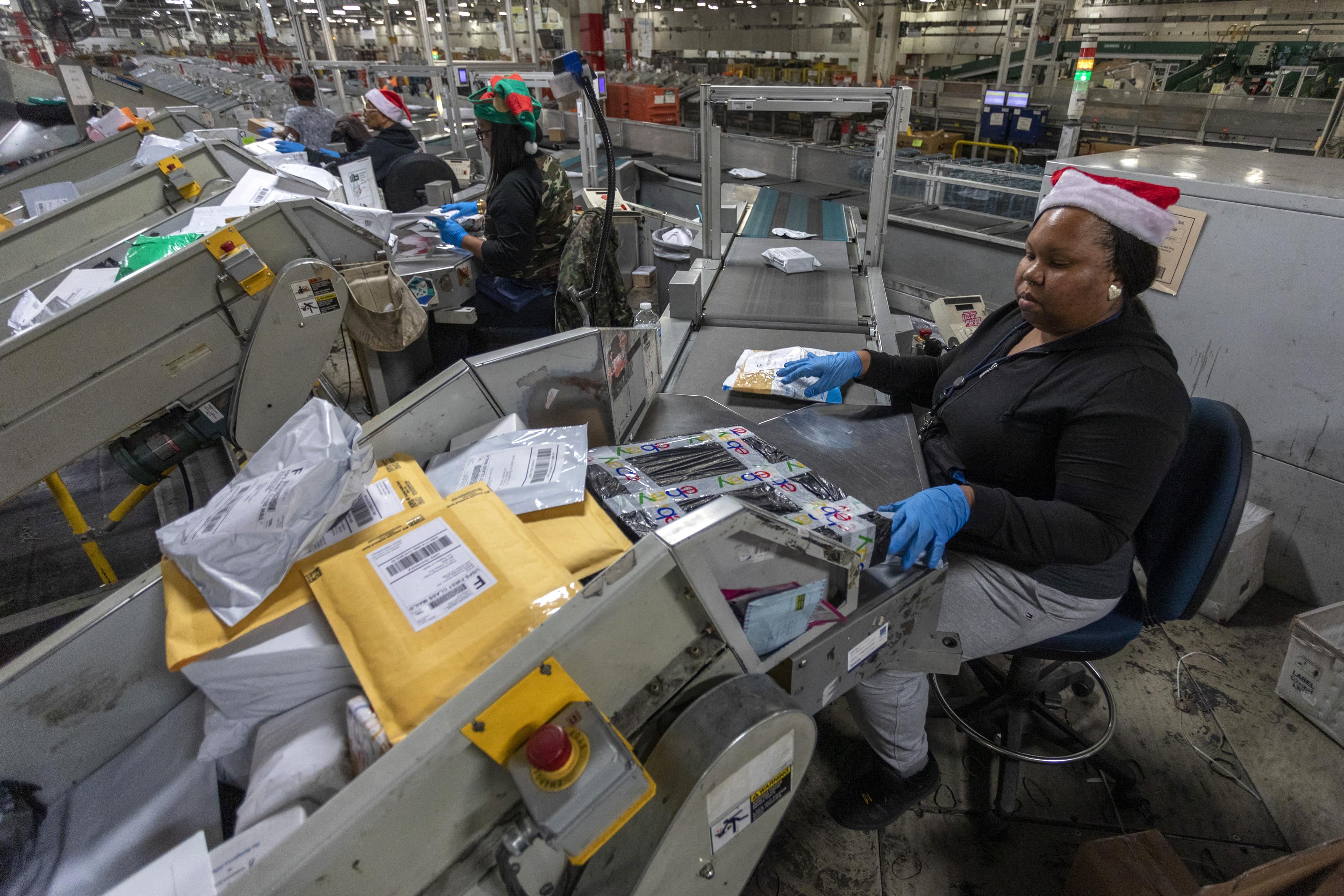 U.S. Postal Service workers scan parcels and pass them along a conveyor belt at the Los Angeles Processing and Distribution Center.