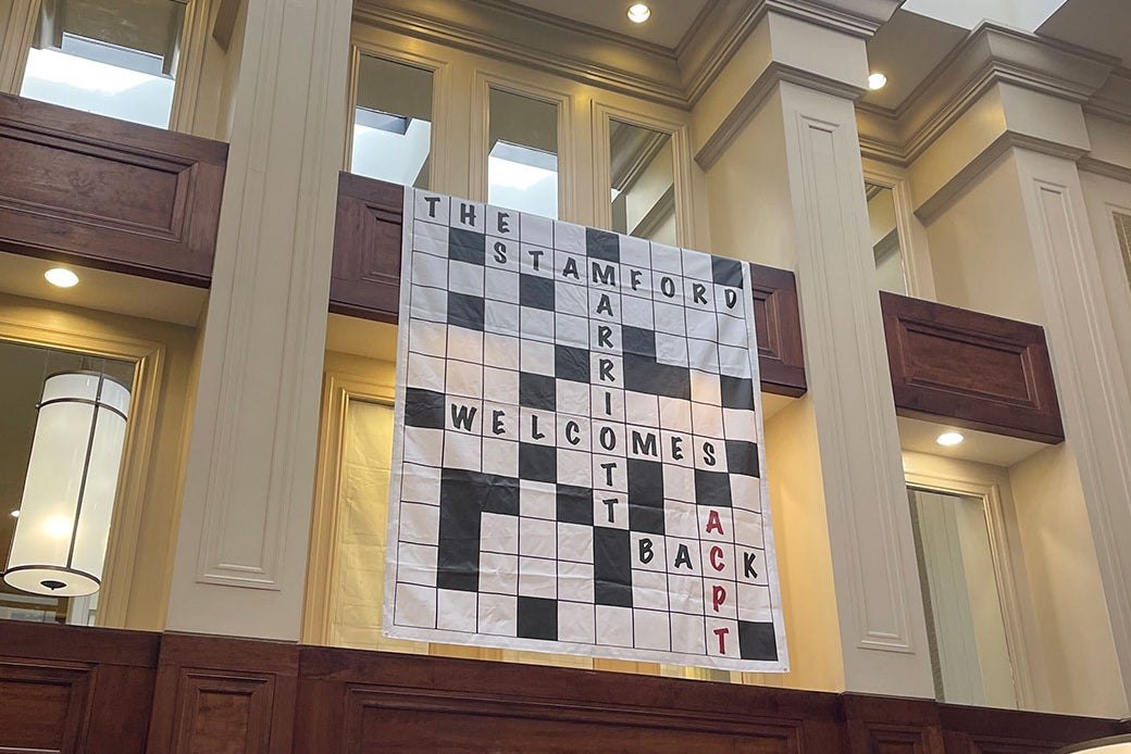 A poster hanging on the wall of a lobby that reads: "The Stamford Marriott Welcomes Back ACPT."