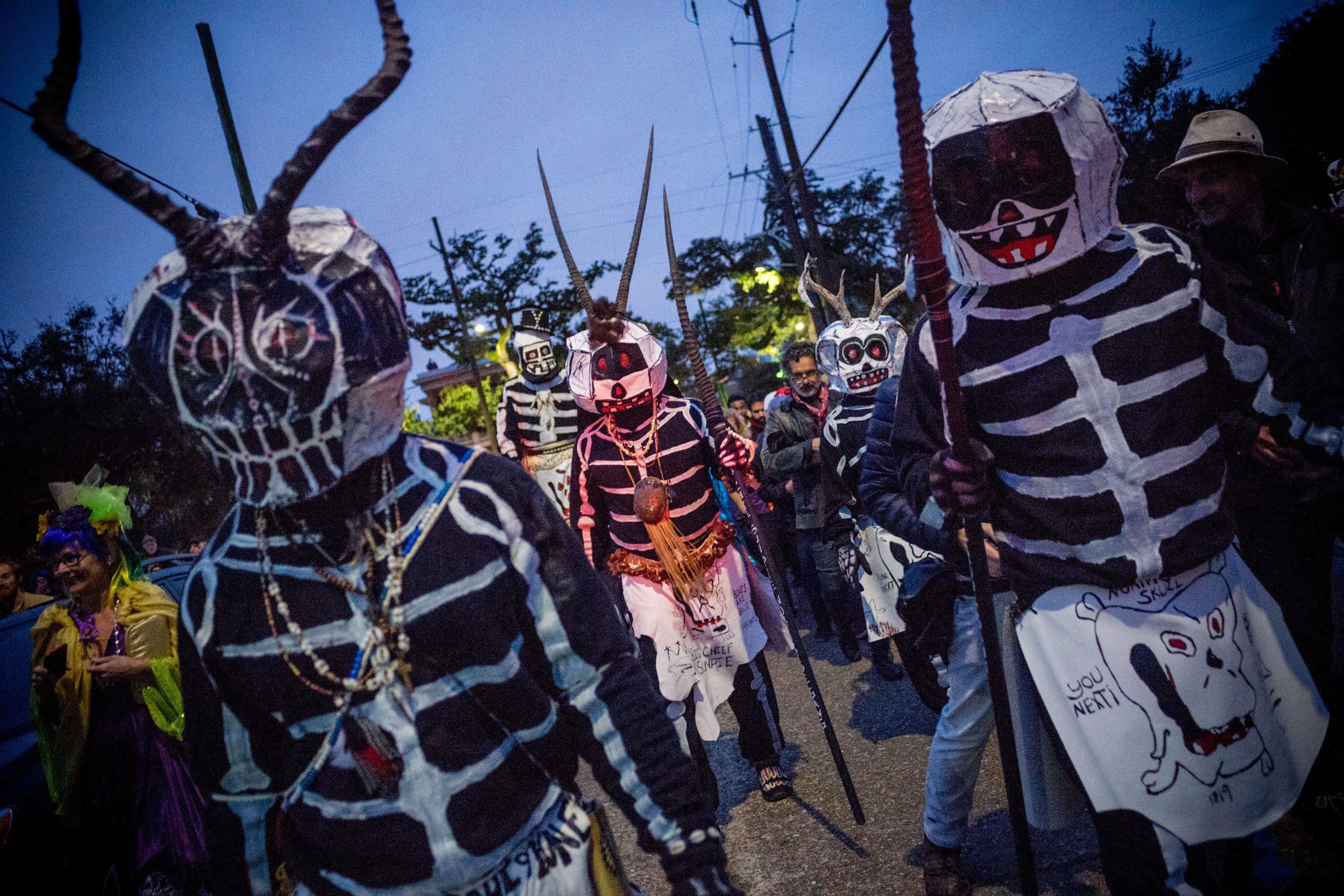 The Skull and Bones Gang, dressed in skeleton costumes, walk down a street.