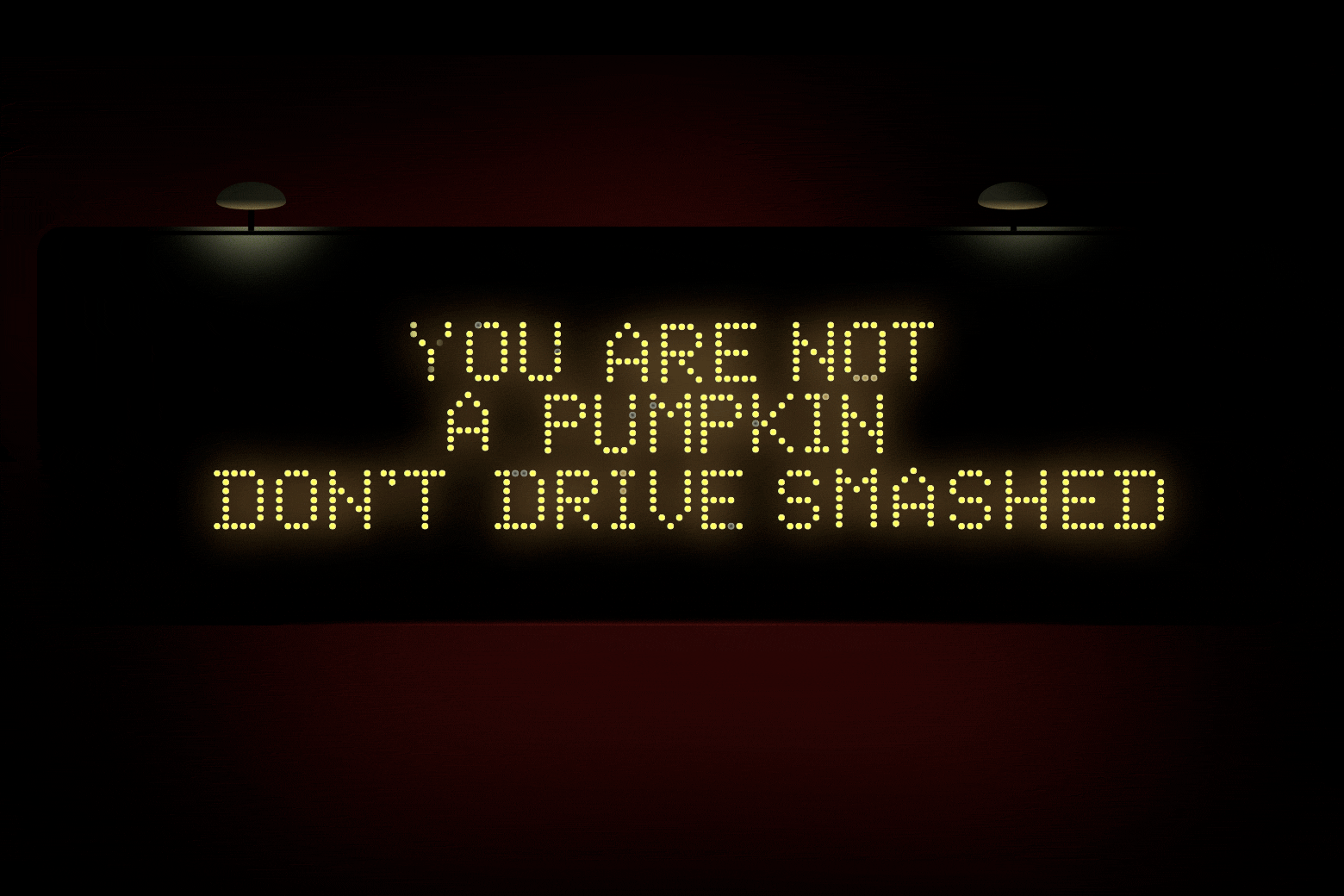 An LED traffic sign flashes through slogans: "You are not a pumpkin don't drive smashed," "This is a sign you should buckle up," "Get your head out of your apps," 