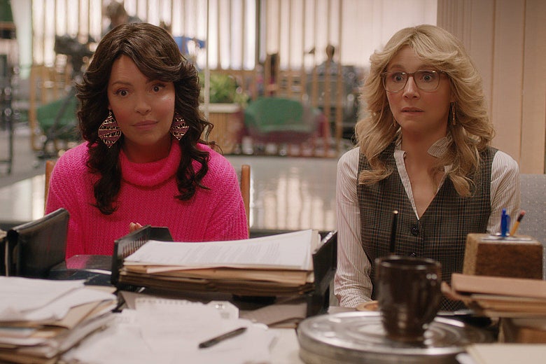 Katherine Heigl and Sarah Chalke sitting at a desk, looking bewildered, with Farrah Fawcett–style hair