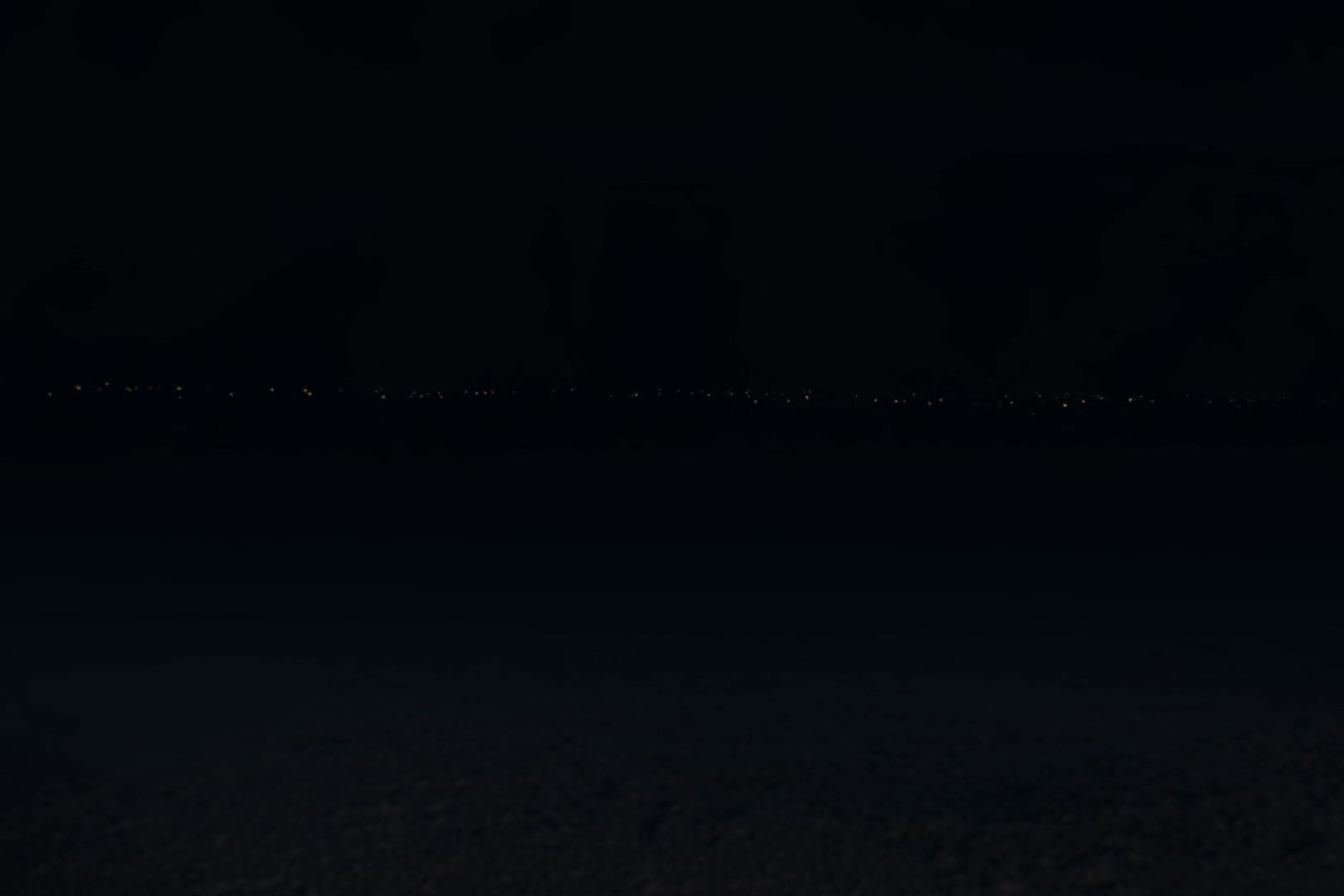 A winter landscape at night, with a very small number of flames, presumably from flaming swords, in the far distance.