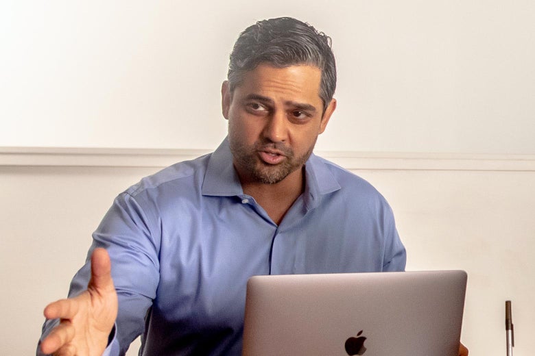 Sri Preston Kulkarni sits in front of a Macbook while talking and gesturing with his hands.