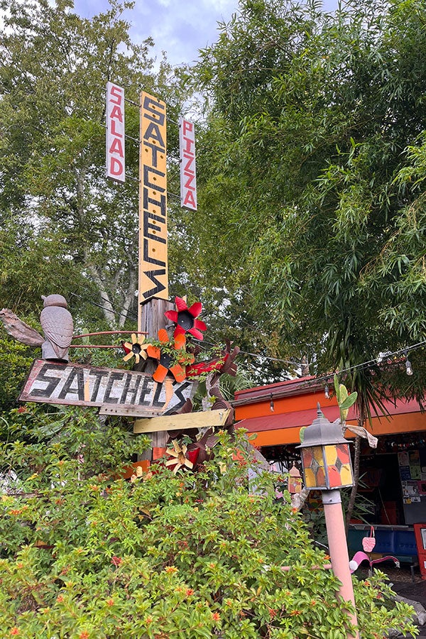 The exterior of Satchel's Pizza, featuring a brightly colored sign that reads: "Satchel's Salad, Pizza."