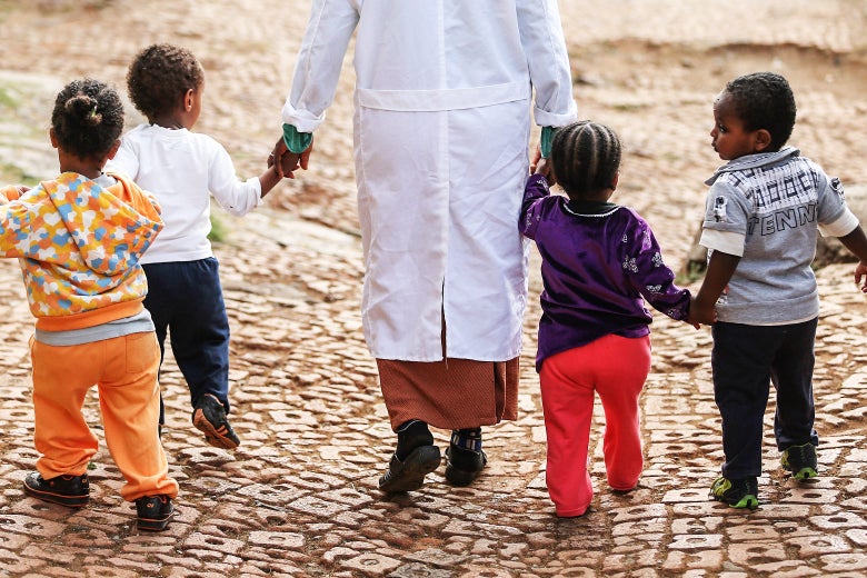 A woman walks with orphans at the AGOHELD orphanage, hospital, training center and school on March 19, 2013 in Addis Ababa, Ethiopia.