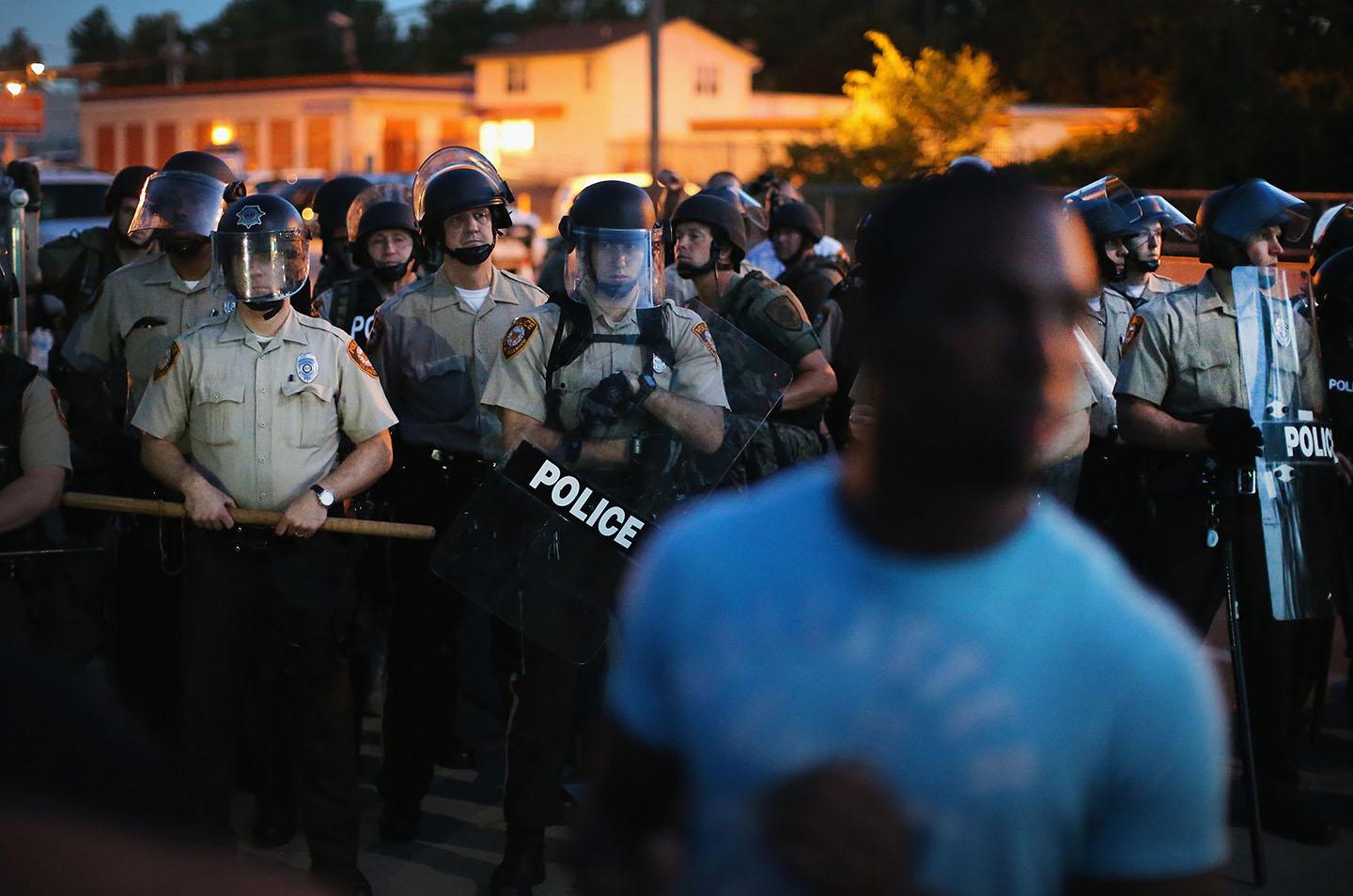 Police stand watch as demonstrators protest the shooting death of teenager Michael Brown on August 13, 2014 in Ferguson, Missouri. 