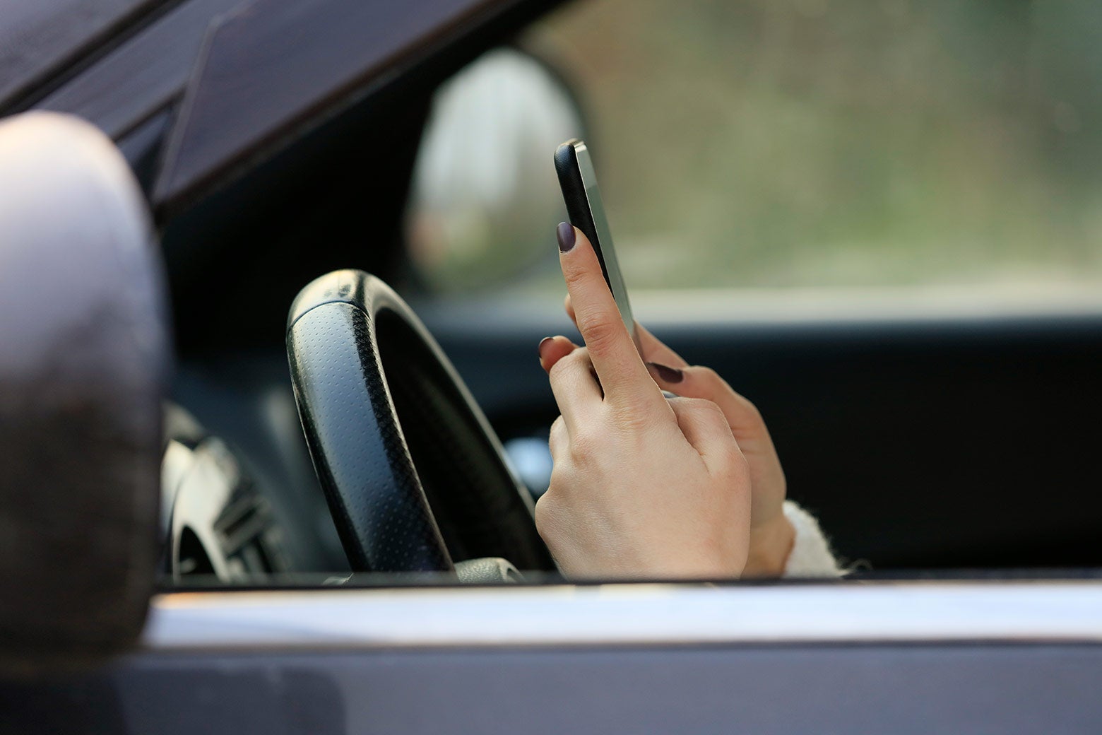 A woman texting while driving a car.