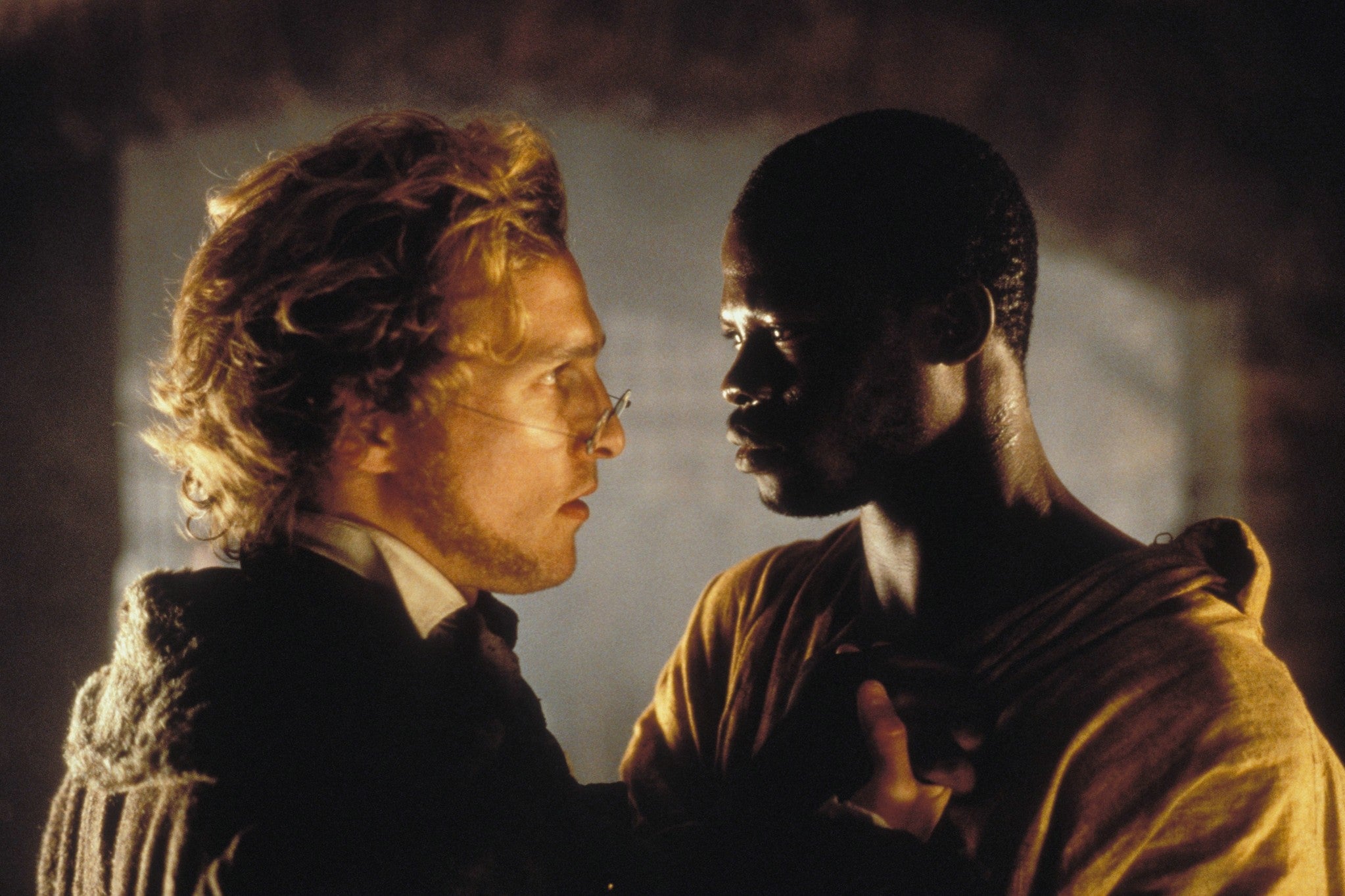 Matthew McConaughey looks at Djimon Hounsou as he grabs the top of his scrappy shirt.
