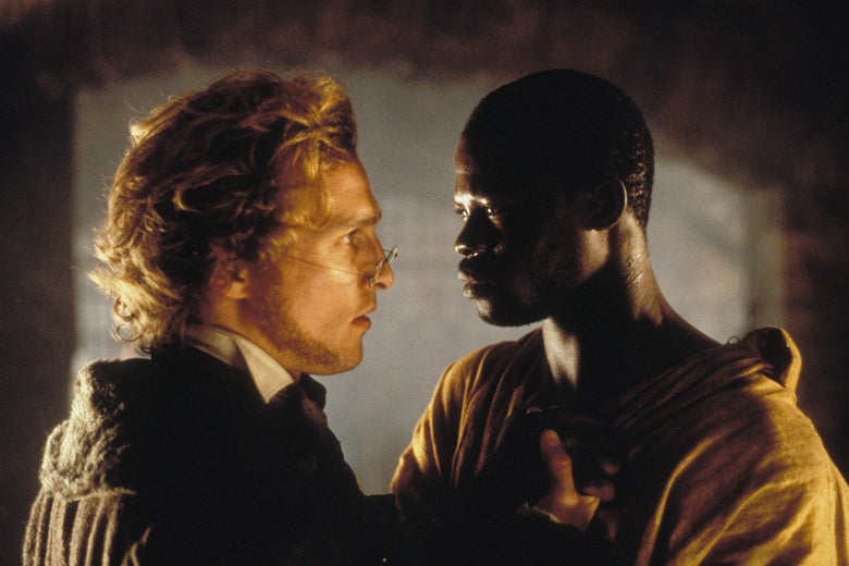 Matthew McConaughey looks at Djimon Hounsou as he grabs the top of his scrappy shirt. 
