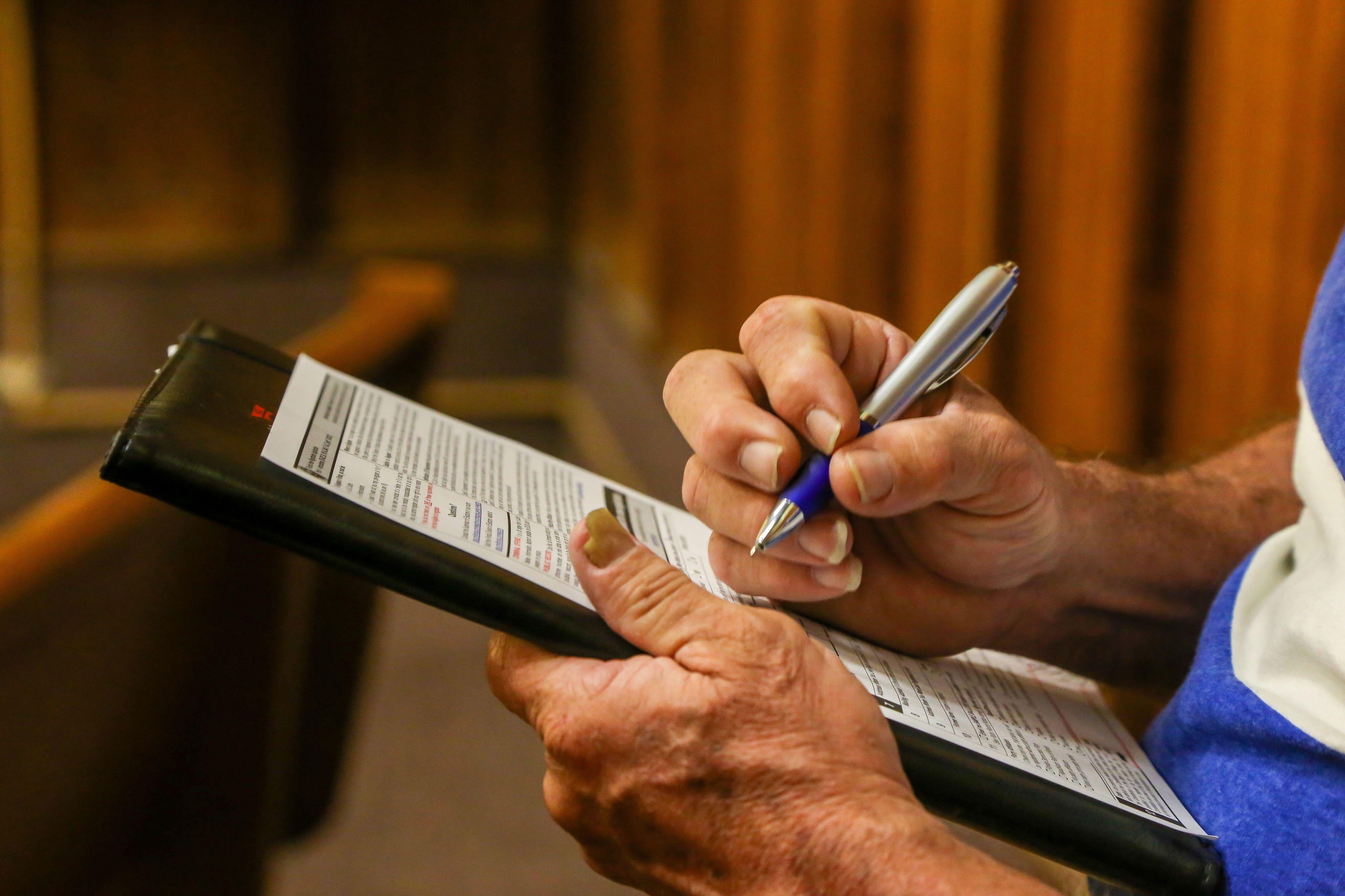 Man filling out a voter registration form in pen