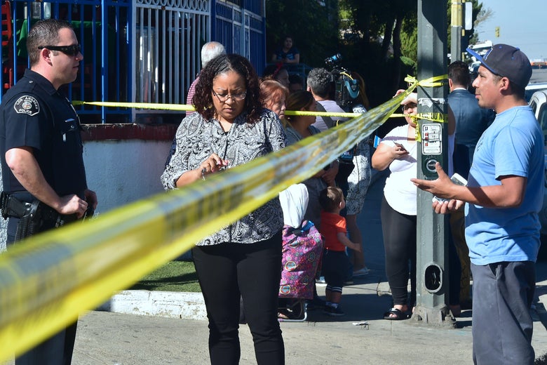 Parents communicate with police officers at a roadblock near Salvador Castro Middle School in Los Angeles, California on February 1, 2018, where two students were wounded, one critically, in a school shooting. Two 15-year-old students in Los Angeles were shot and wounded in class Thursday, according to witnesses and local media, in the latest school shooting to hit the United States. A boy was shot in the head, while a girl was hit in the wrist, according to reports from the scene. Local news agency CNS reported that a 'young woman,' possibly a fellow student, had been arrested.  / AFP PHOTO / Frederic J. Brown        (Photo credit should read FREDERIC J. BROWN/AFP/Getty Images)