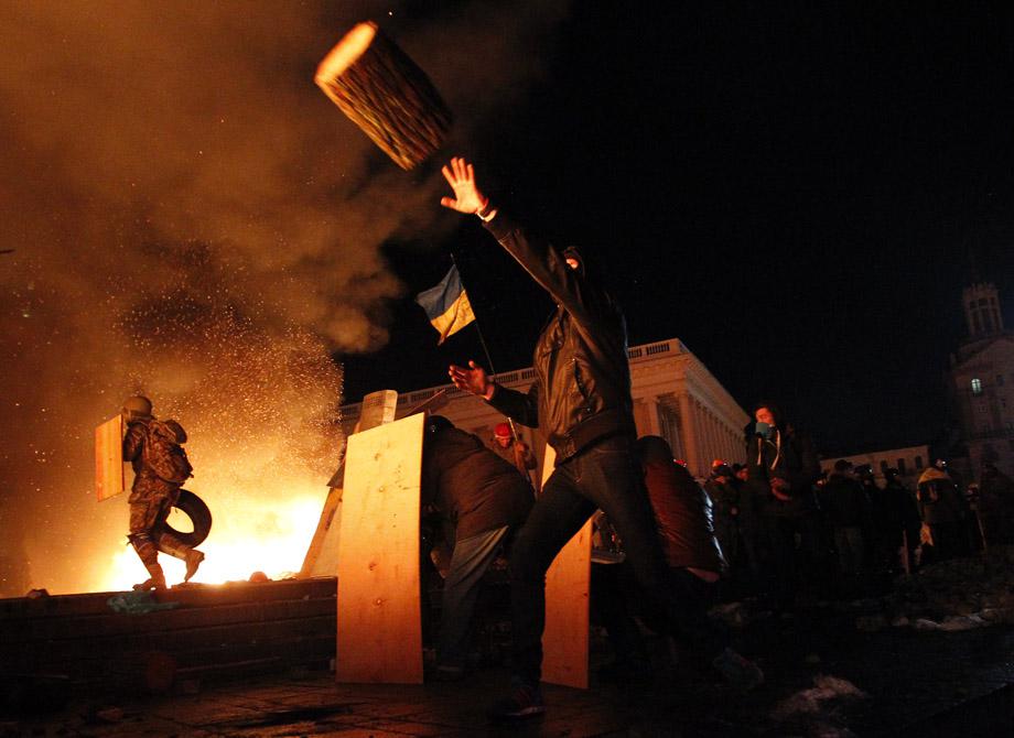 A protester throws a log during clashes with riot police at Independence Square in Kiev 