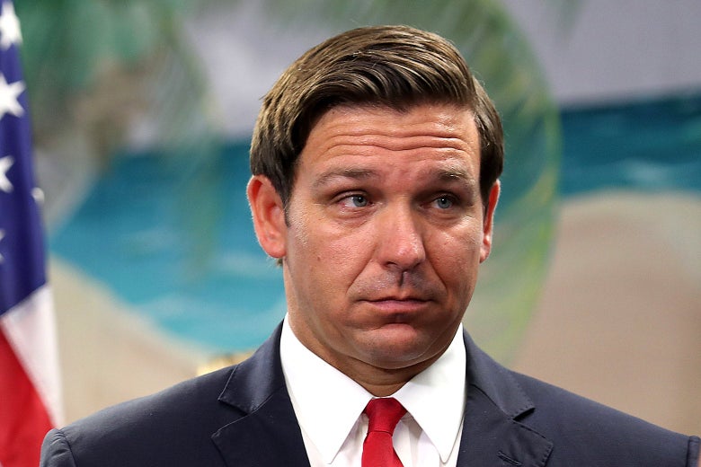 Ron DeSantis standing with a beach scene on the wall behind him