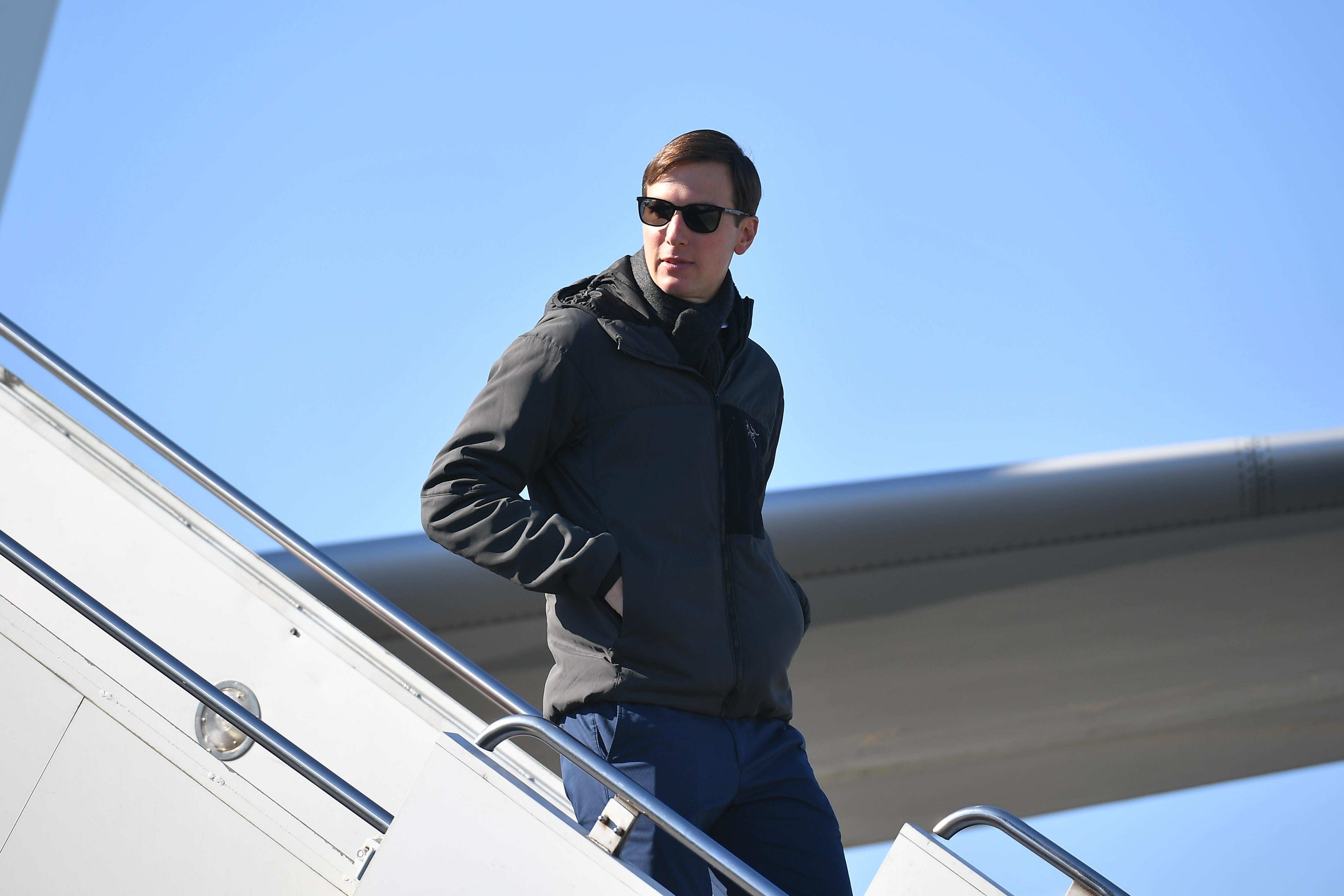 Jared Kushner walks down steps off of an airplane.