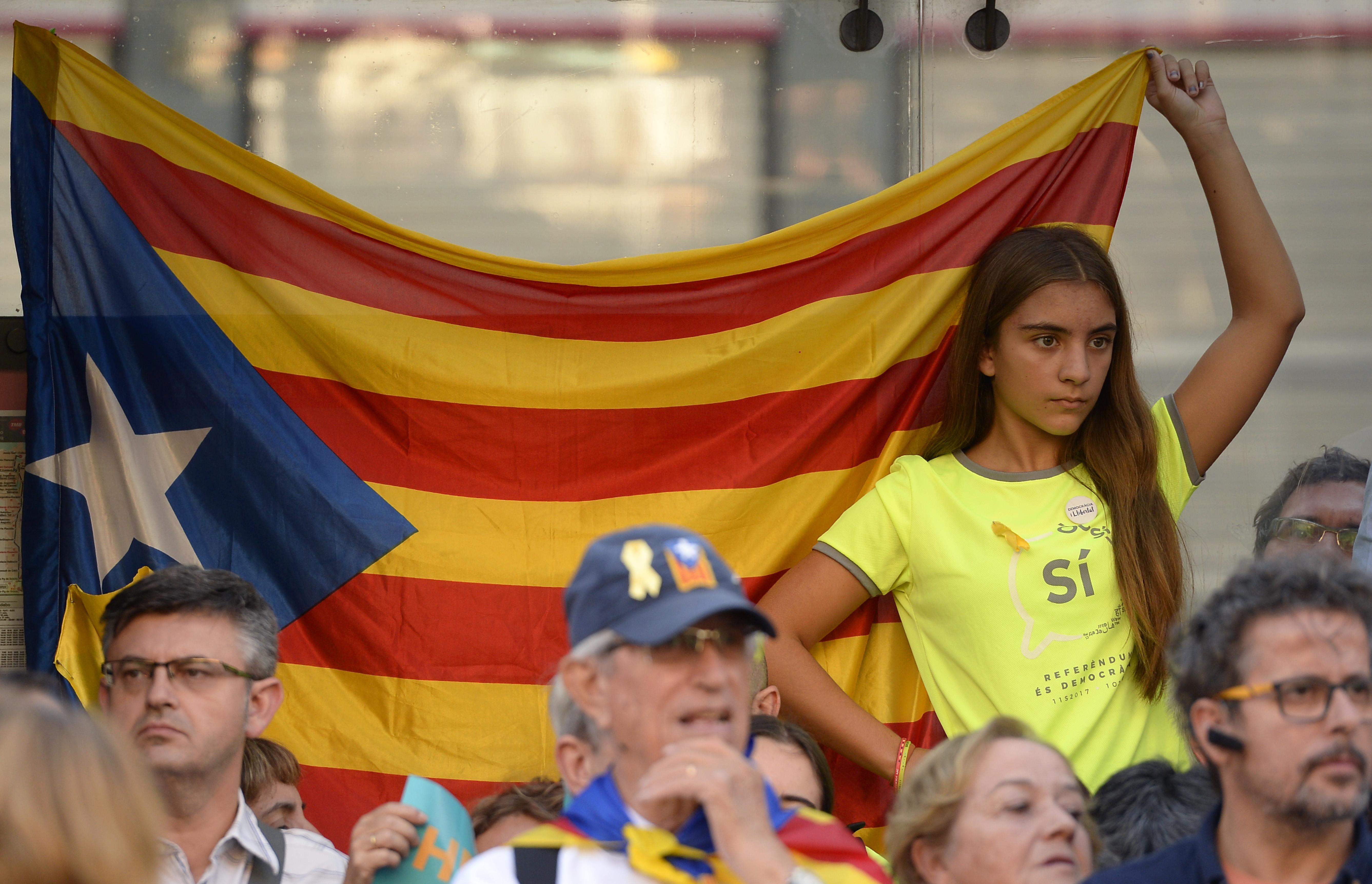 Women hold Spanish, Catalan and European flags during a demonstration against Catalonia's independence in front of the European Parliament building