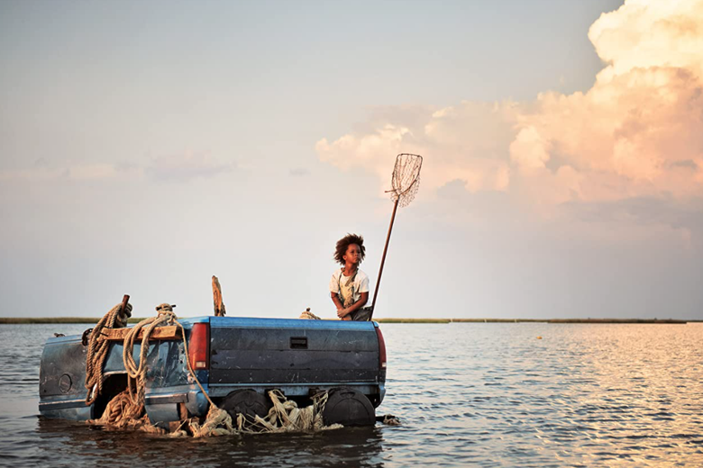 Quvenzhané Wallis sits on the bed of a pickup truck floating in a vast lake of water.