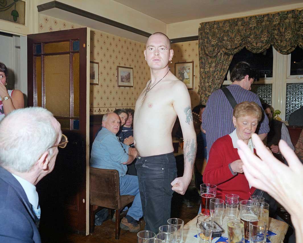 A bare chested skinhead postures for the camera in a pub in Bacup, Lancashire. 