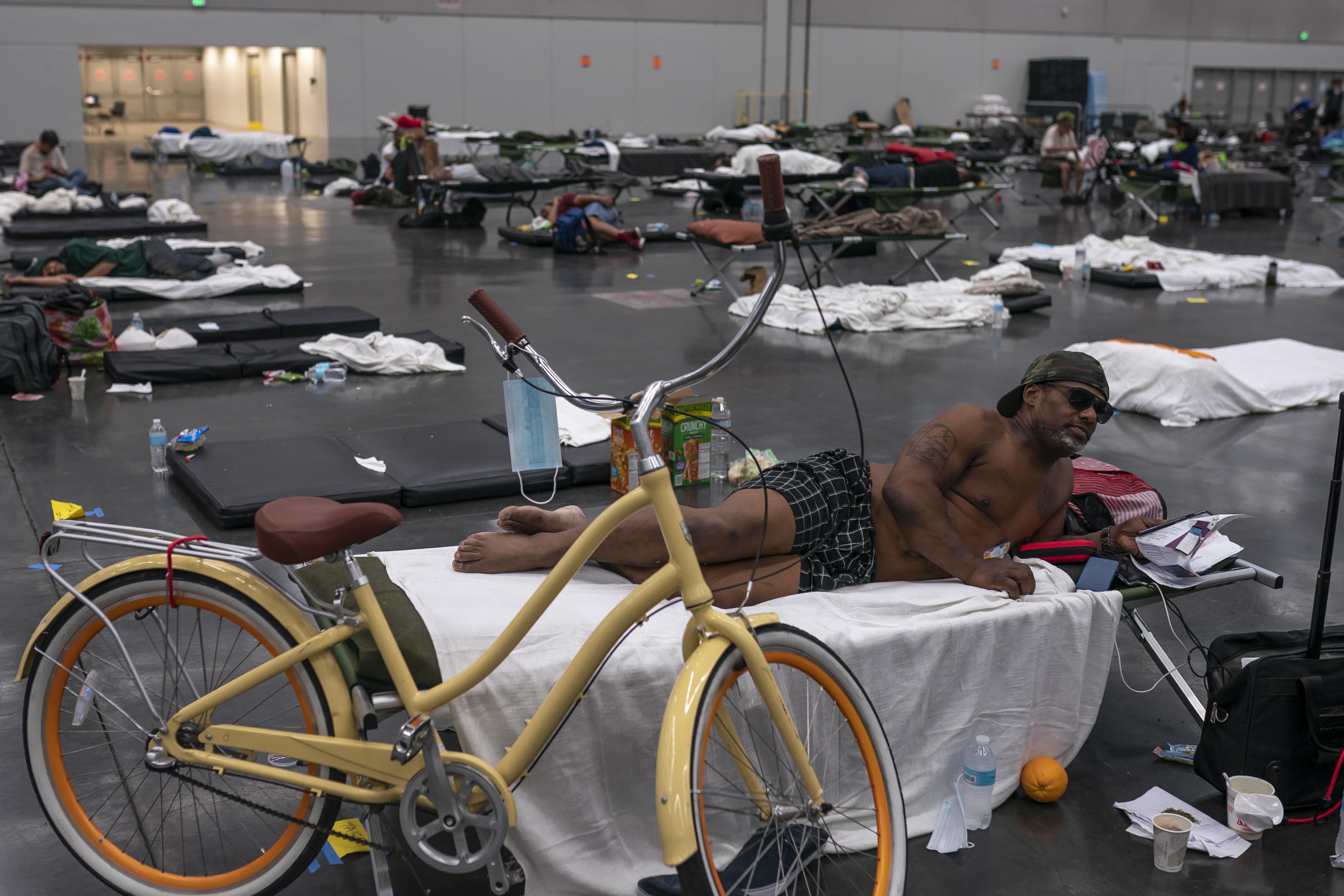 A man rests on a cot in a cooling center, along with his bike. 