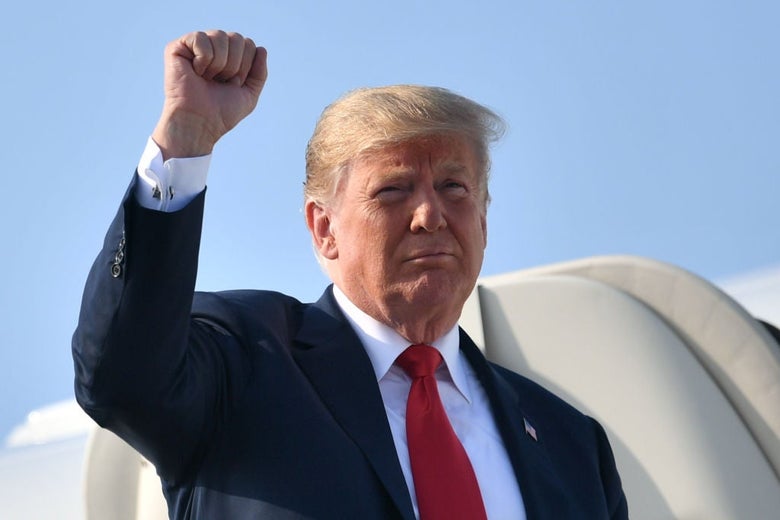 Trump holds his fist aloft as he exits Air Force One.