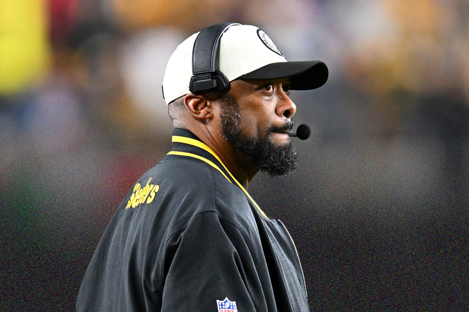 Steelers coach Mike Tomlin looking worried on the sideline, in a white cap and headset and Steelers jacket, pursing his lips and looking upward.