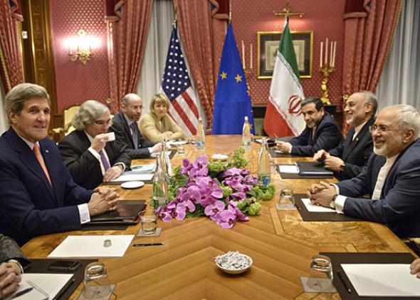 U.S. Secretary of State John Kerry (left) and Iranian Foreign Minister Mohammad Javad Zarif (right) wait with others for a meeting at the Beau-Rivage Palace Hotel on March 28, 2015, in Lausanne, Switzerland