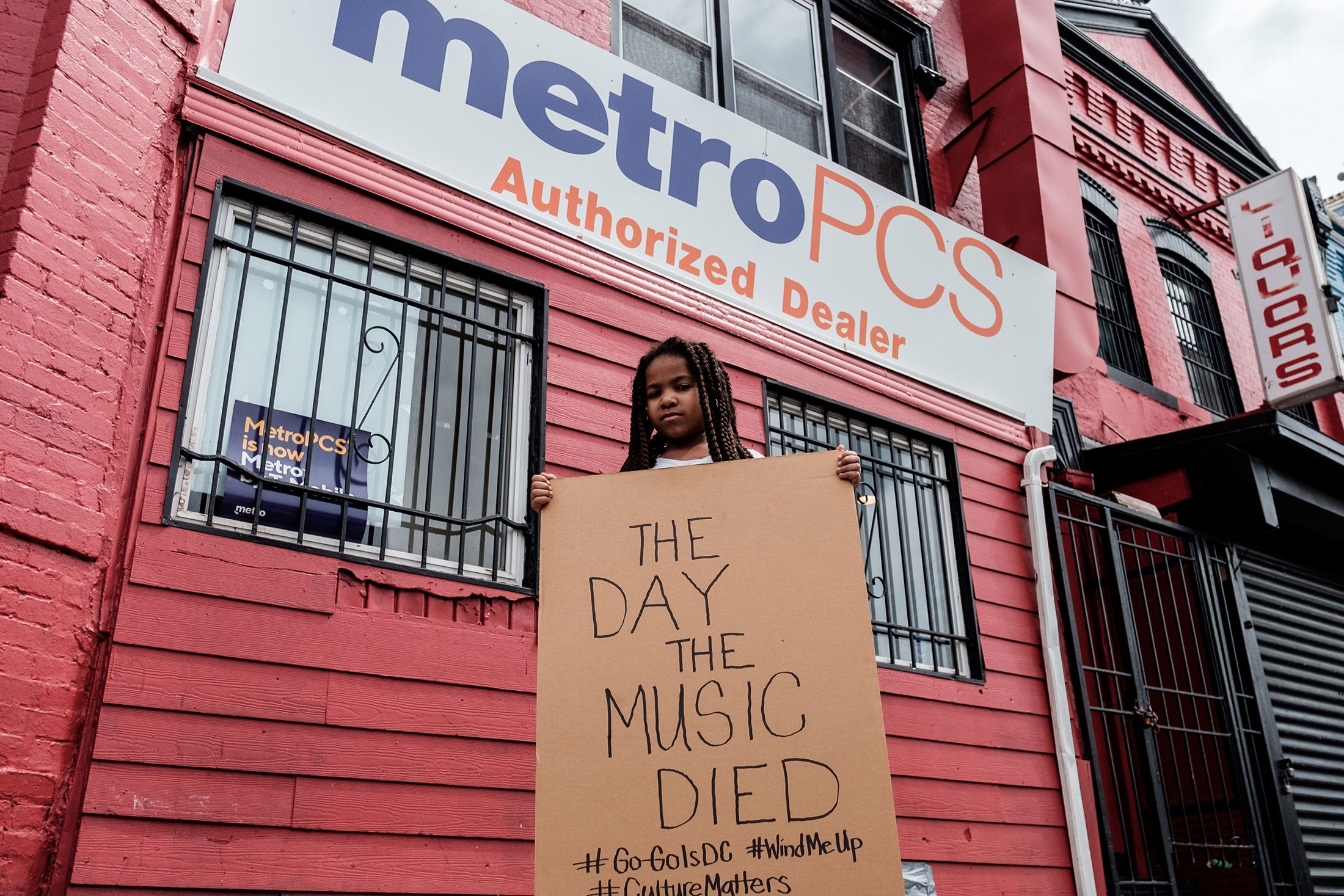 Ryan-Camille Guyot holds a cardboard sign saying, "The day the music died."