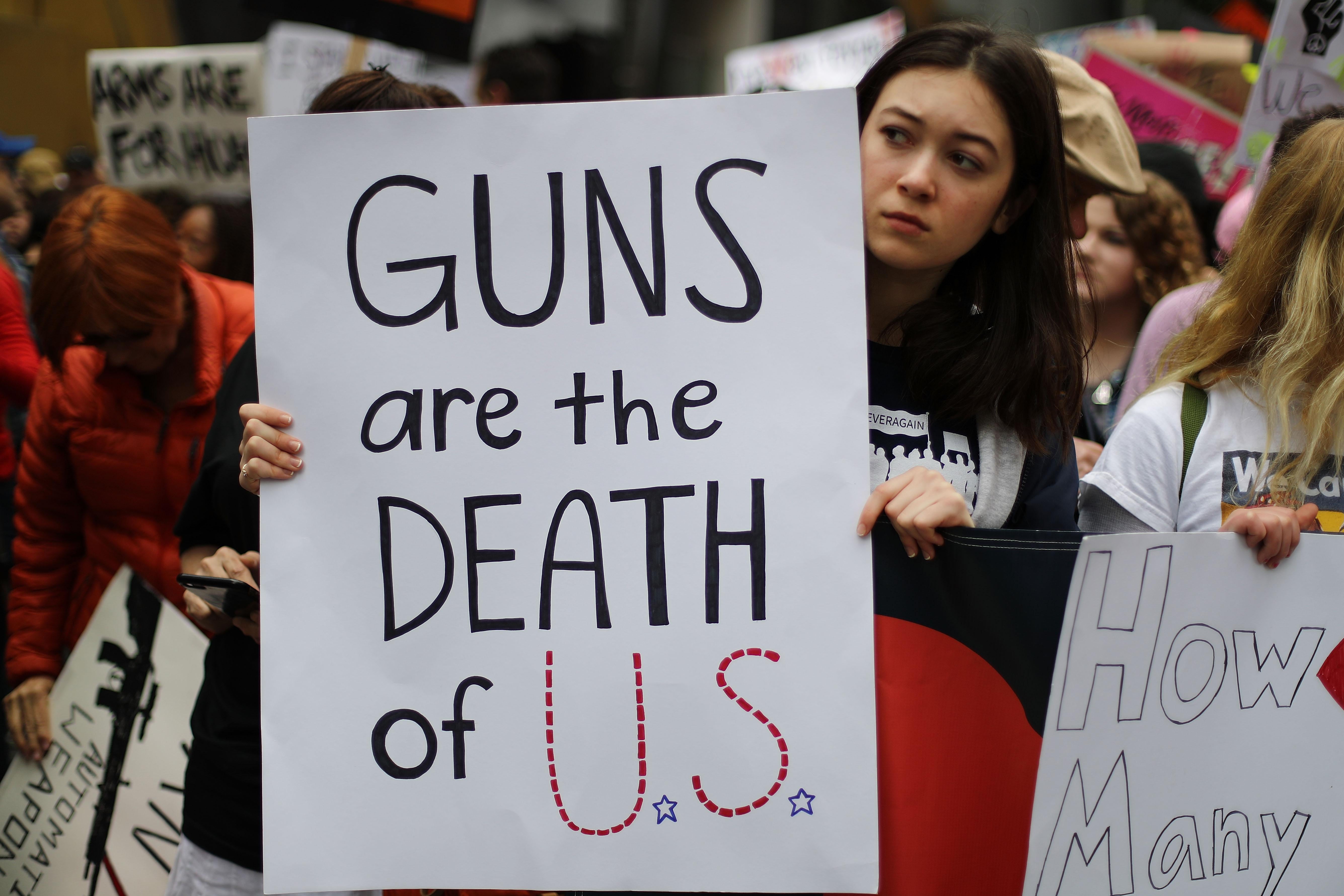 A sign reads, "Guns are the death of U.S."
