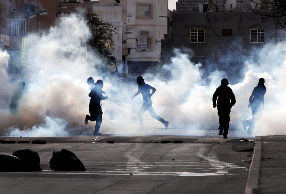 Bahraini anti-government protesters react to tear gas fired by riot police in Sanabis, Bahrain, on March 14, 2013. Protests and clashes erupted in opposition areas nationwide Thursday with government opponents observing a "Dignity Strike," blocking roads, closing shops, protesting, and staying home from work and school, called by the more radical February 14 youth group.