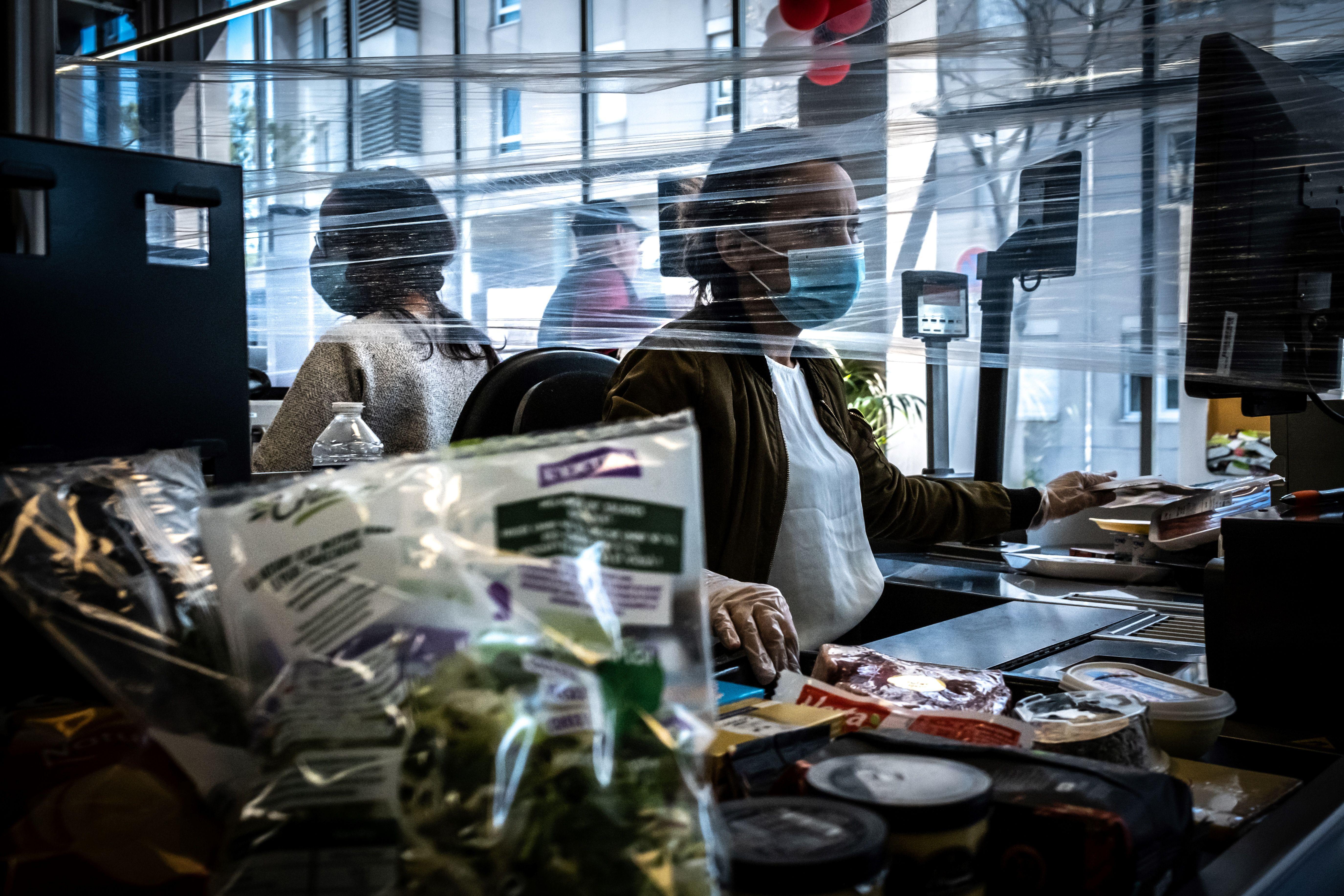 A cashier works wearing a face mask in a supermarket.