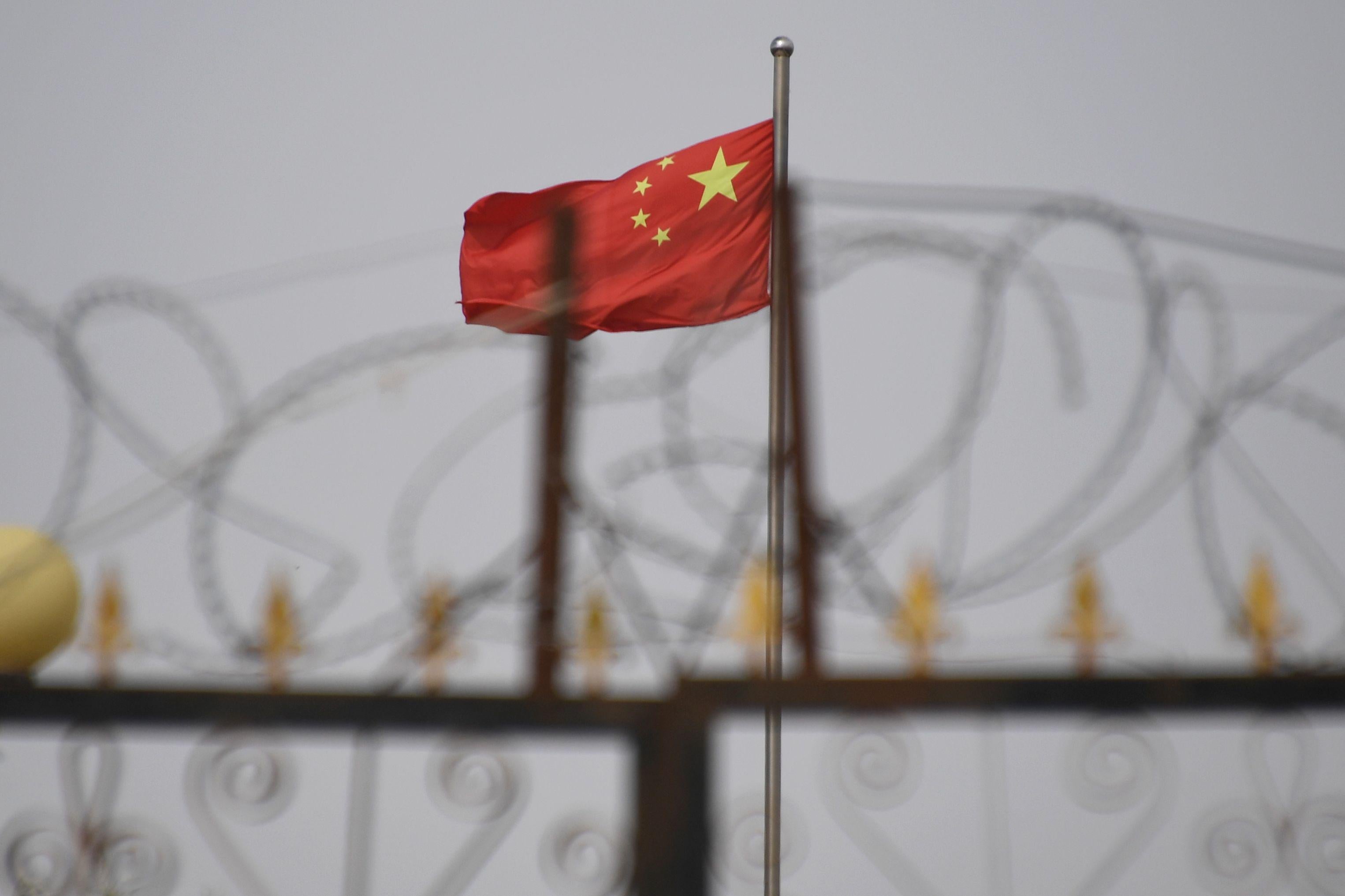 A Chinese flag seen behind razor wire.