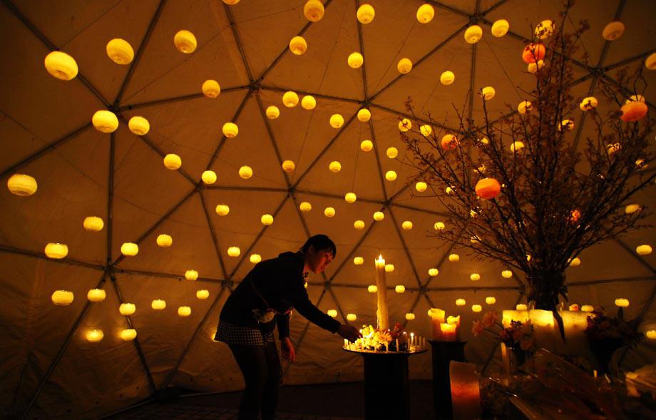 A woman lights candles to pay tribute to the victims of the March 11 earthquake and tsunami at a make-shift alter in a park in Tokyo.