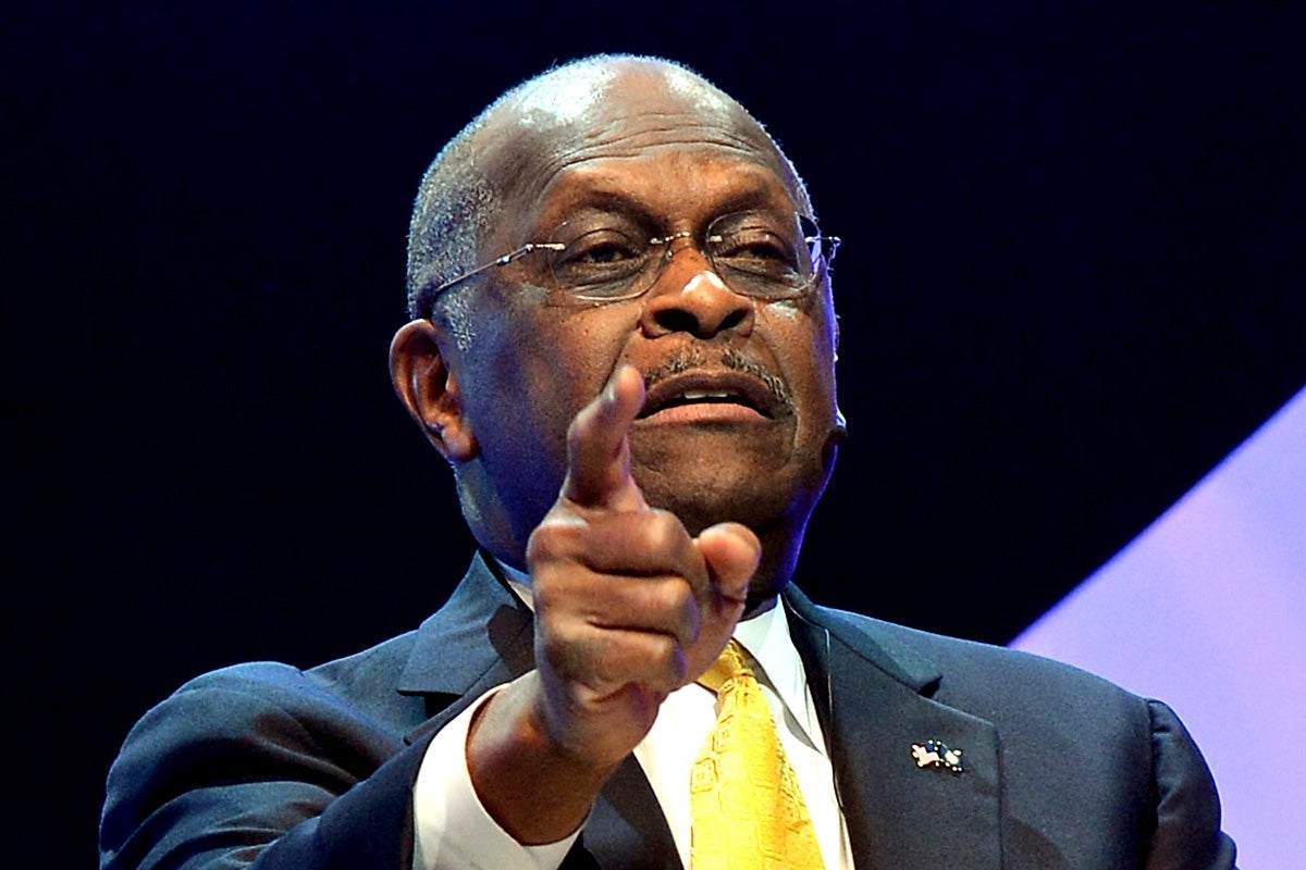 Herman Cain points toward the audience at a live talk.