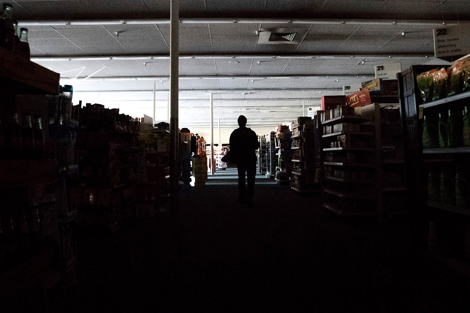 A man stands in the darkened aisles of a CVS.