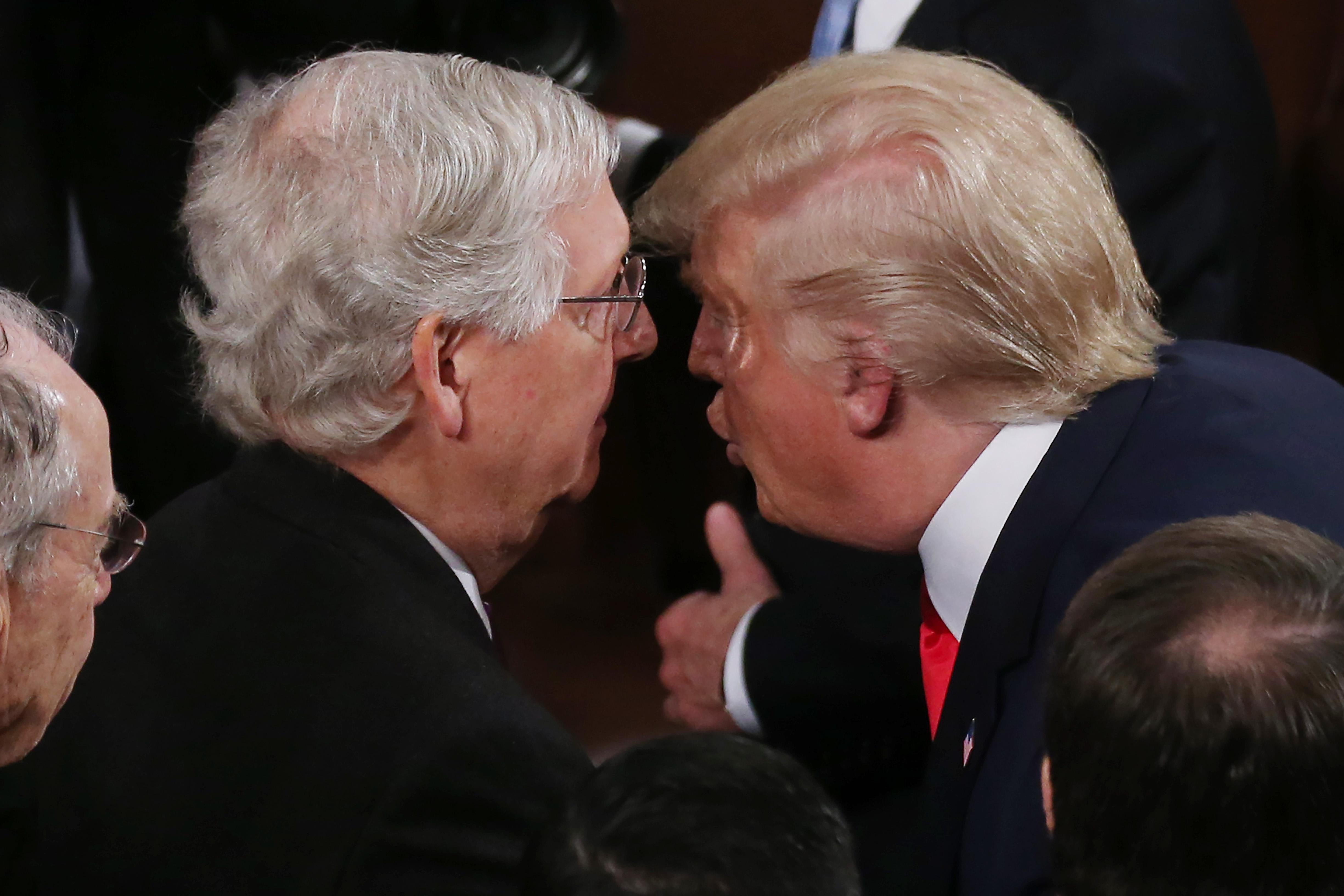 Trump leans in closely to speak to Mitch McConnell.