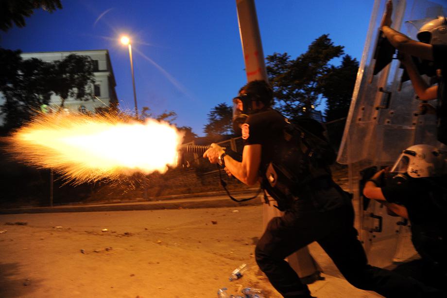 A Turkish riot police officer fires tear gas during clashes with protestors between Taksim and Besiktas in Istanbul on June 3, 2013. 