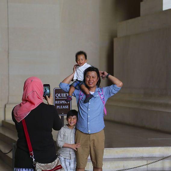 A tourist family pose for an iPhone photoshoot beneath the Lincoln Memorial.