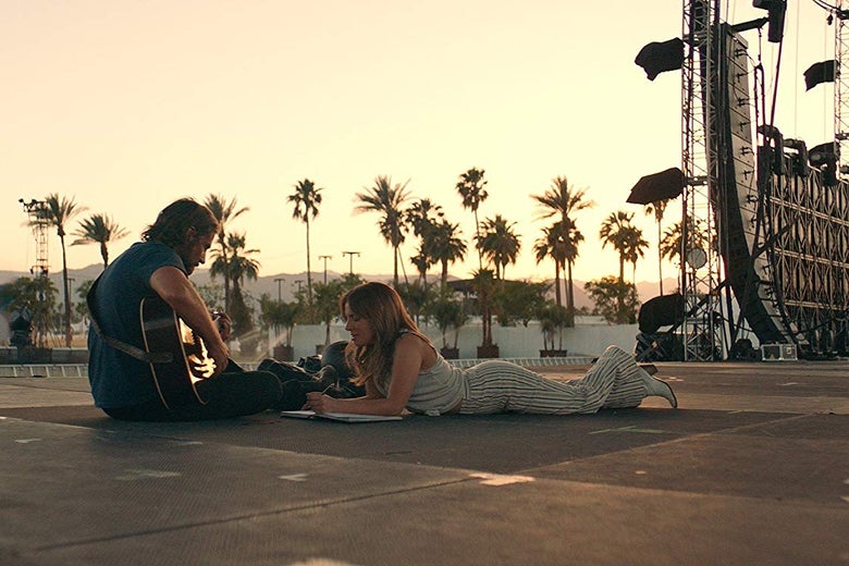 In a still from a scene cut from the original theatrical version of A Star Is Born, Bradley Cooper and Lady Gaga sit on an empty stage together writing music.